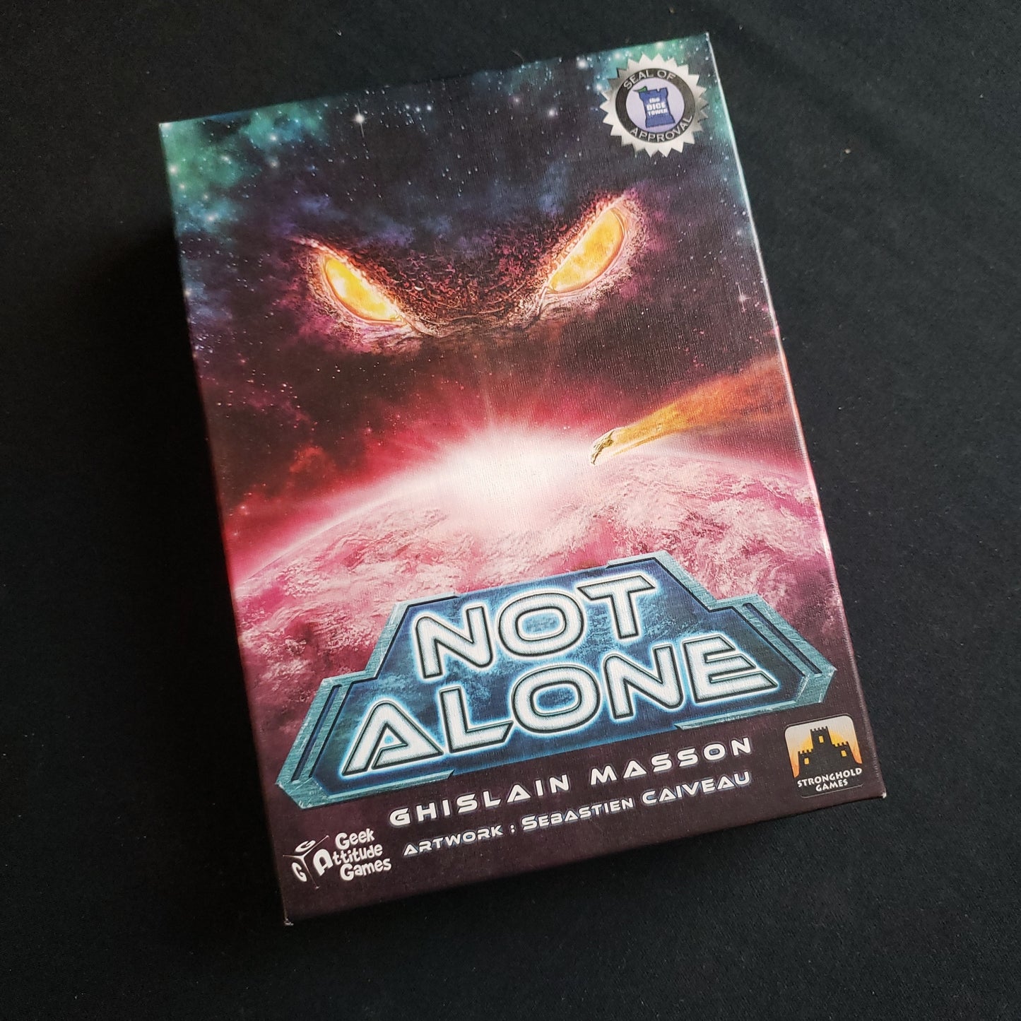 Image shows the front cover of the box of the Not Alone card game