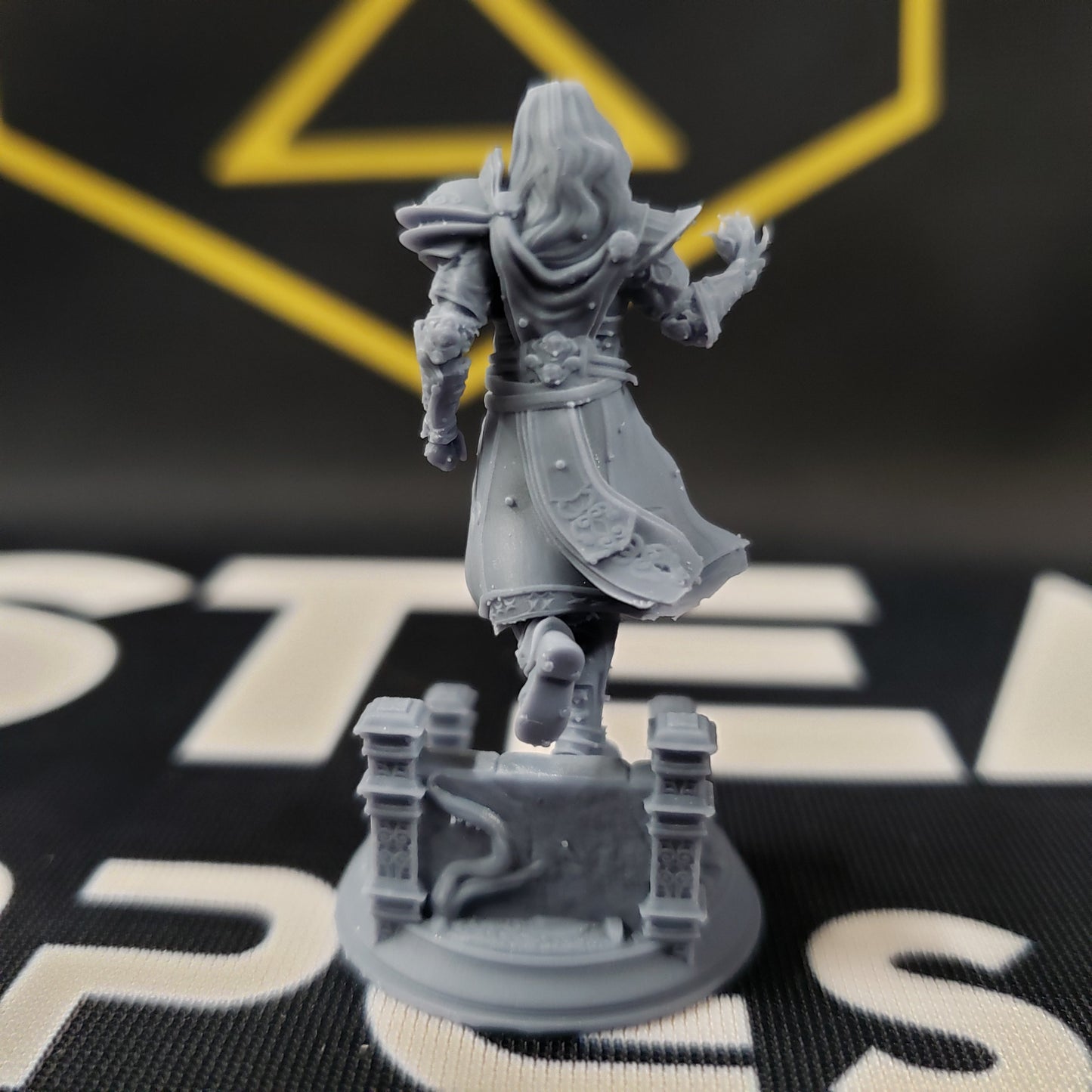 Image shows the back of a 3D printed human wizard gaming miniature, walking down some steps and conjuring a spell with one hand