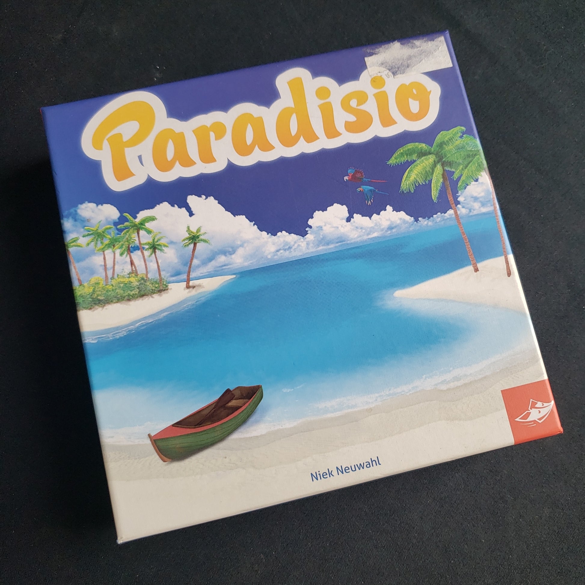 Image shows the front cover of the box of the Paradisio board game