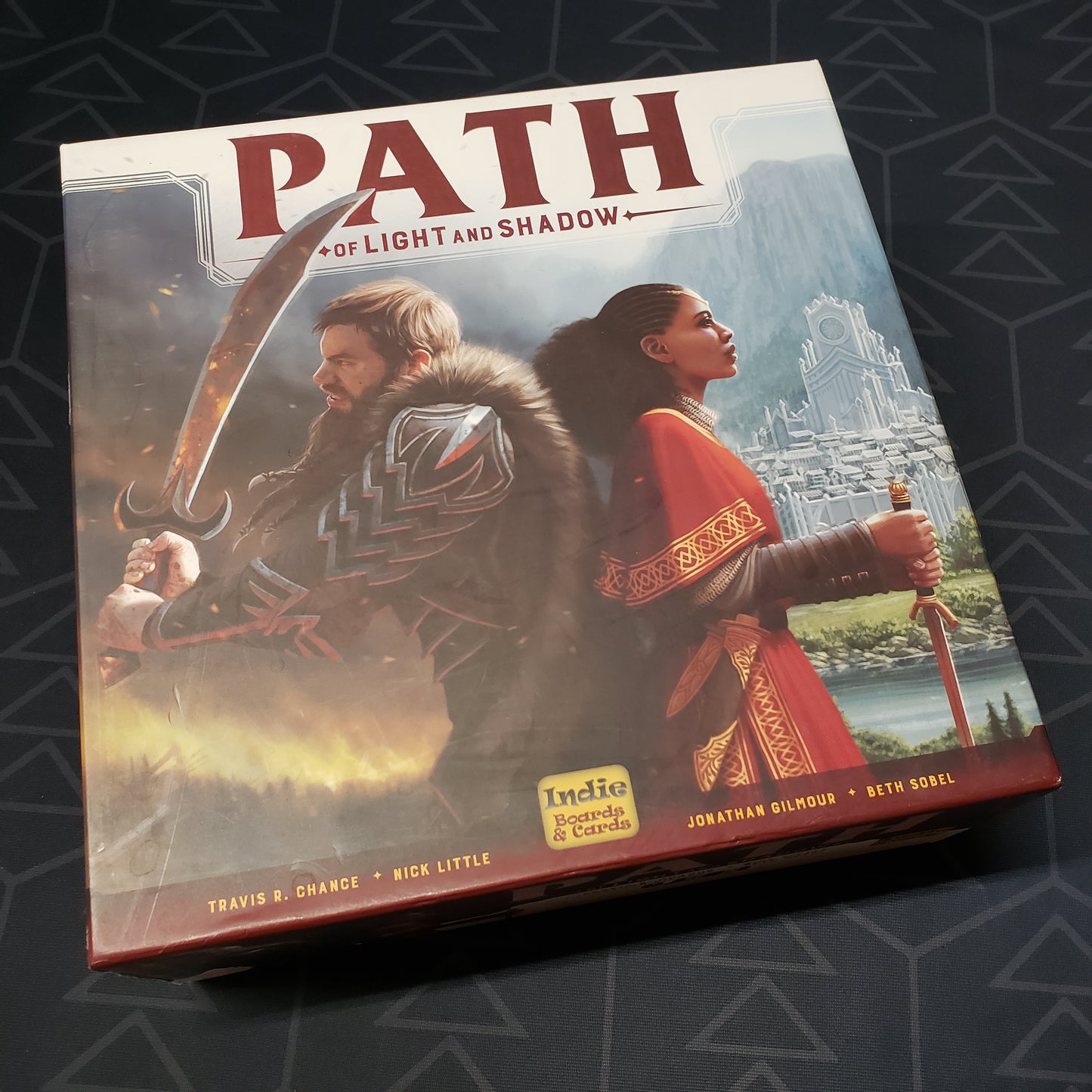 Image shows the front cover of the box of the Path of Light and Shadow board game