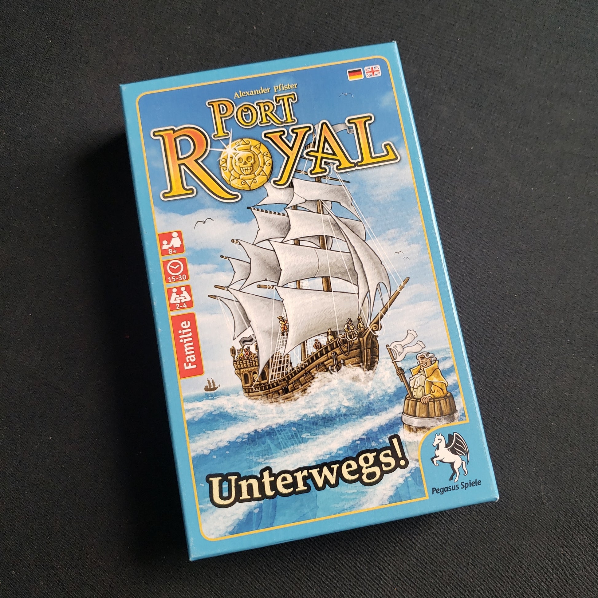 Image shows the front cover of the box of the Port Royal: Unterwegs! card game