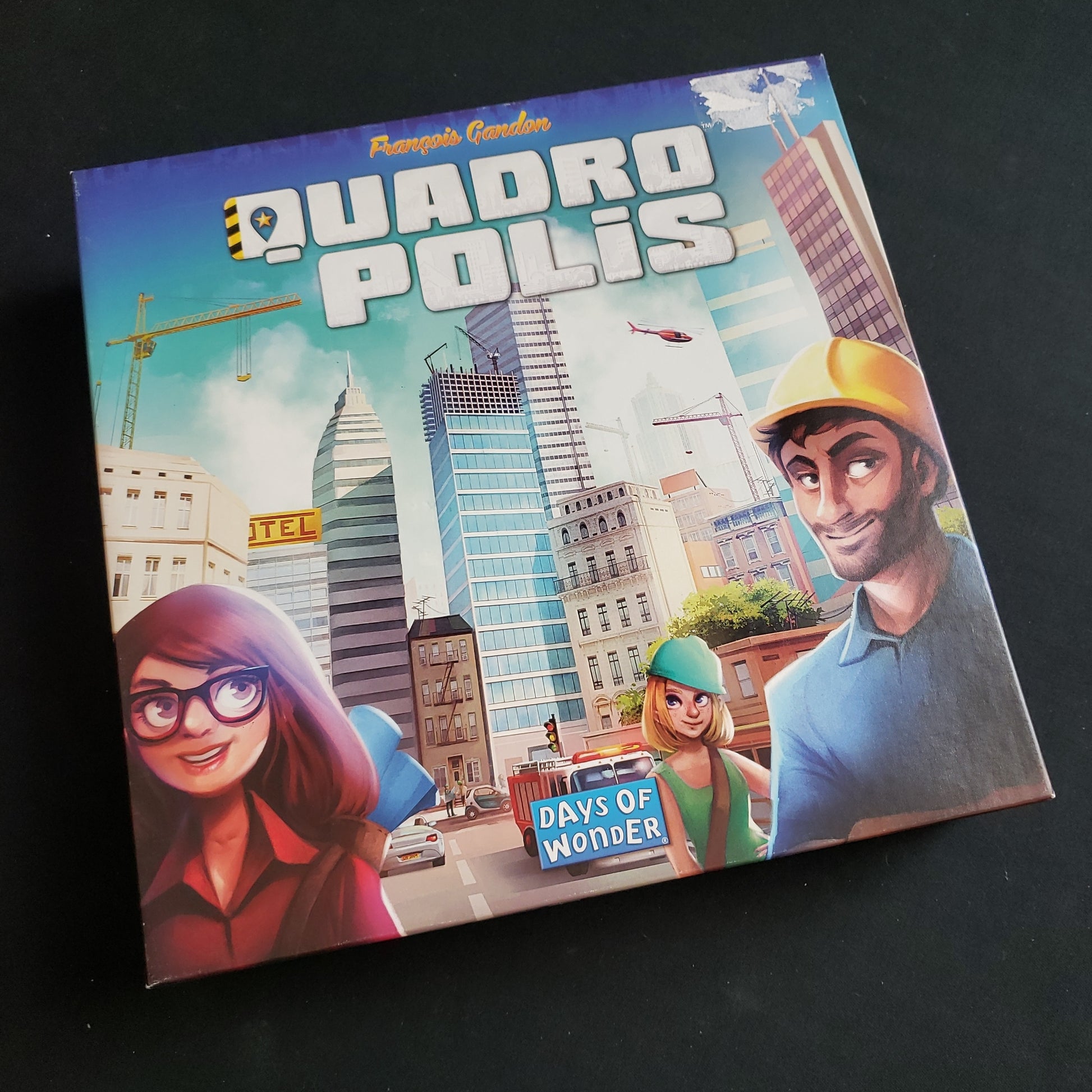 Image shows the front cover of the box of the Quadropolis board game