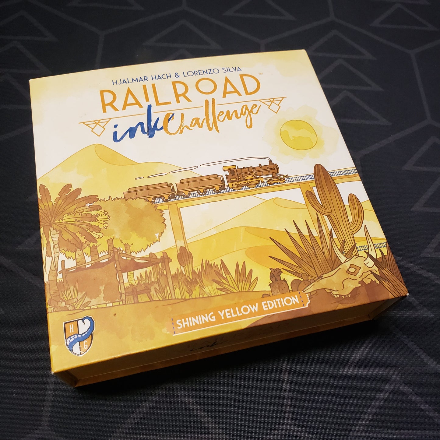 Image shows the front cover of the box for the Railroad Ink Challenge: Shining Yellow Edition board game