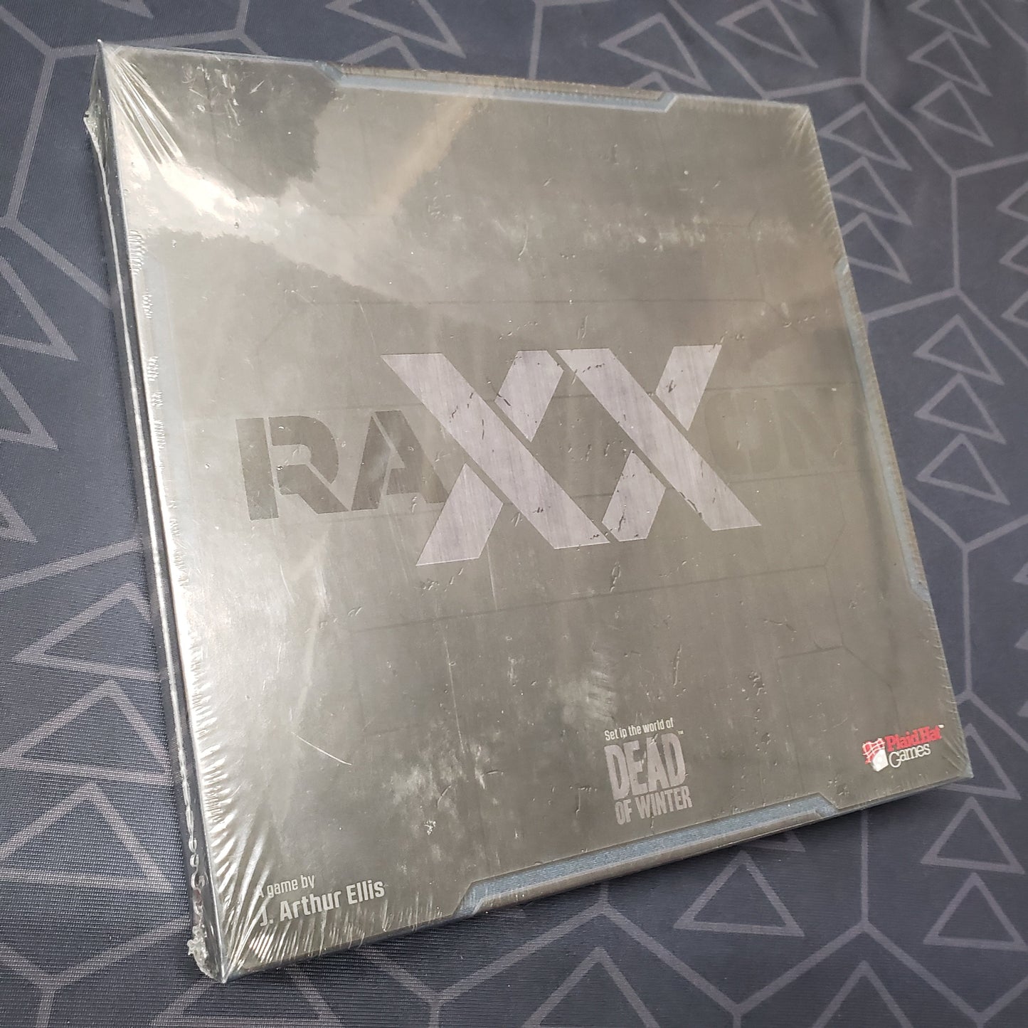 Image shows the front cover of the box of the Raxxon board game
