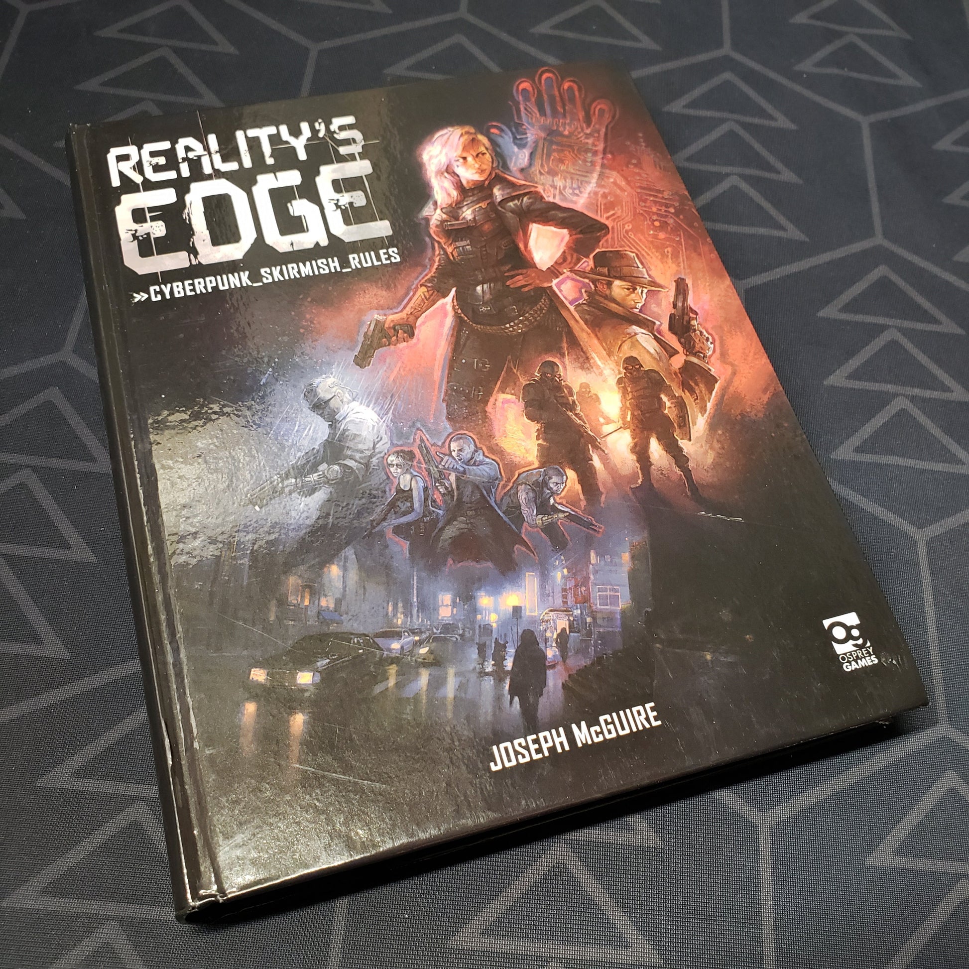 Image shows the front cover of the Reality's Edge: Cyberpunk Skirmish Rules wargaming book