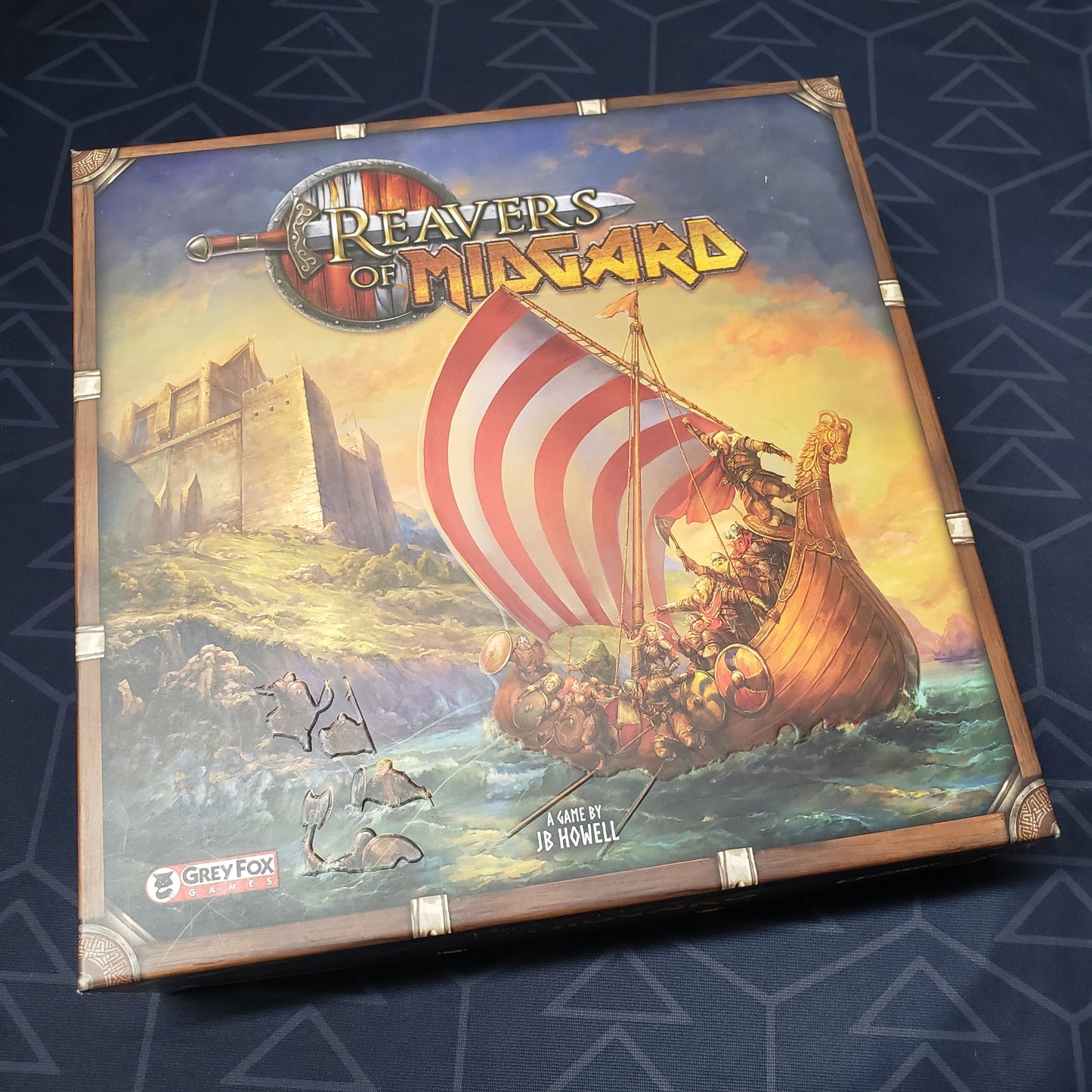 Image shows the front cover of the box of the Reavers of Midgard board game