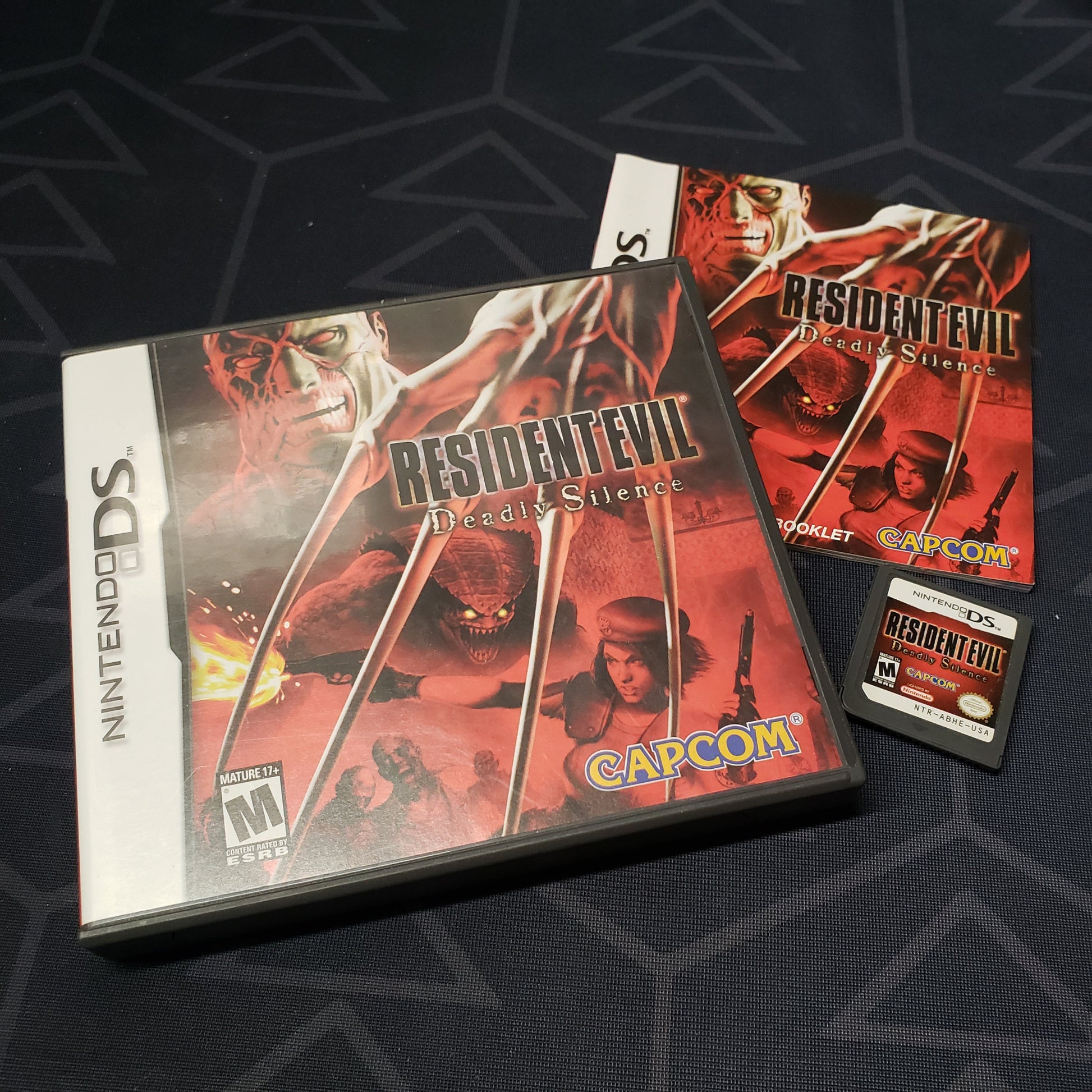 Image shows the case, manual and cartridge for the video game Resident Evil: Deadly Silence for Nintendo DS