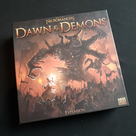 Image shows the front cover of the box of the Dawn & Demons expansion for the board game Rise of the Necromancers