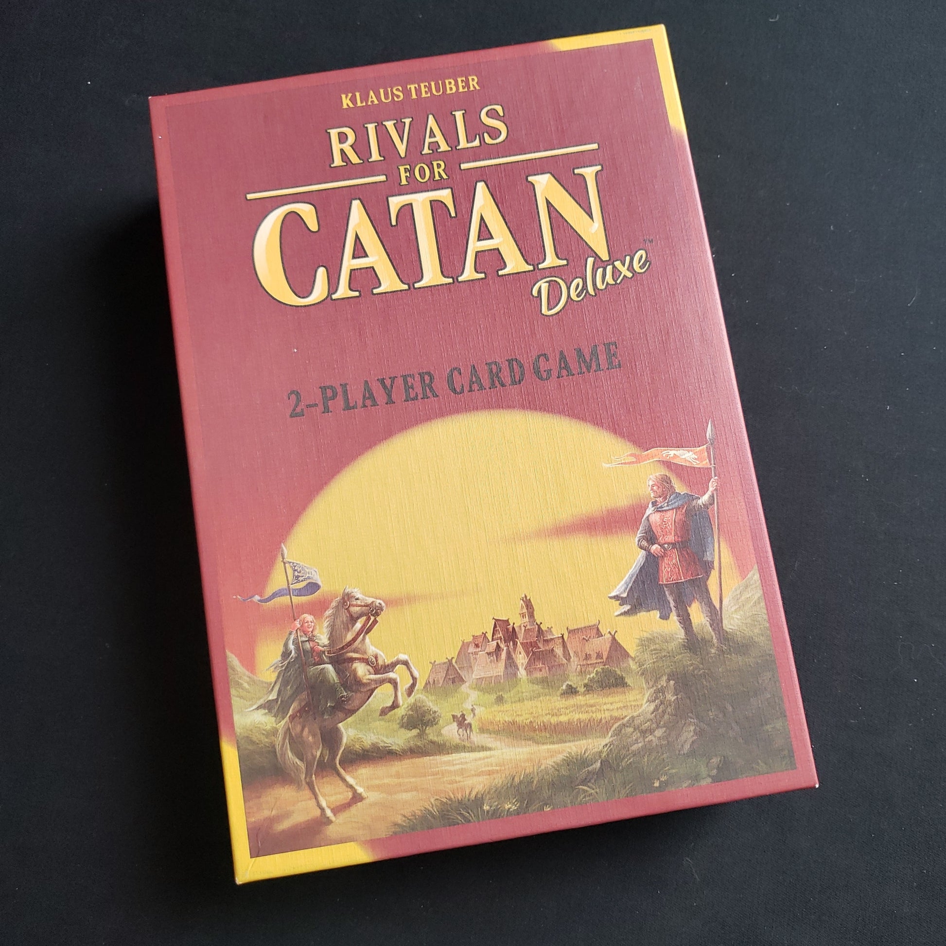 Image shows the front cover of the box of the Rivals for Catan: Deluxe card game