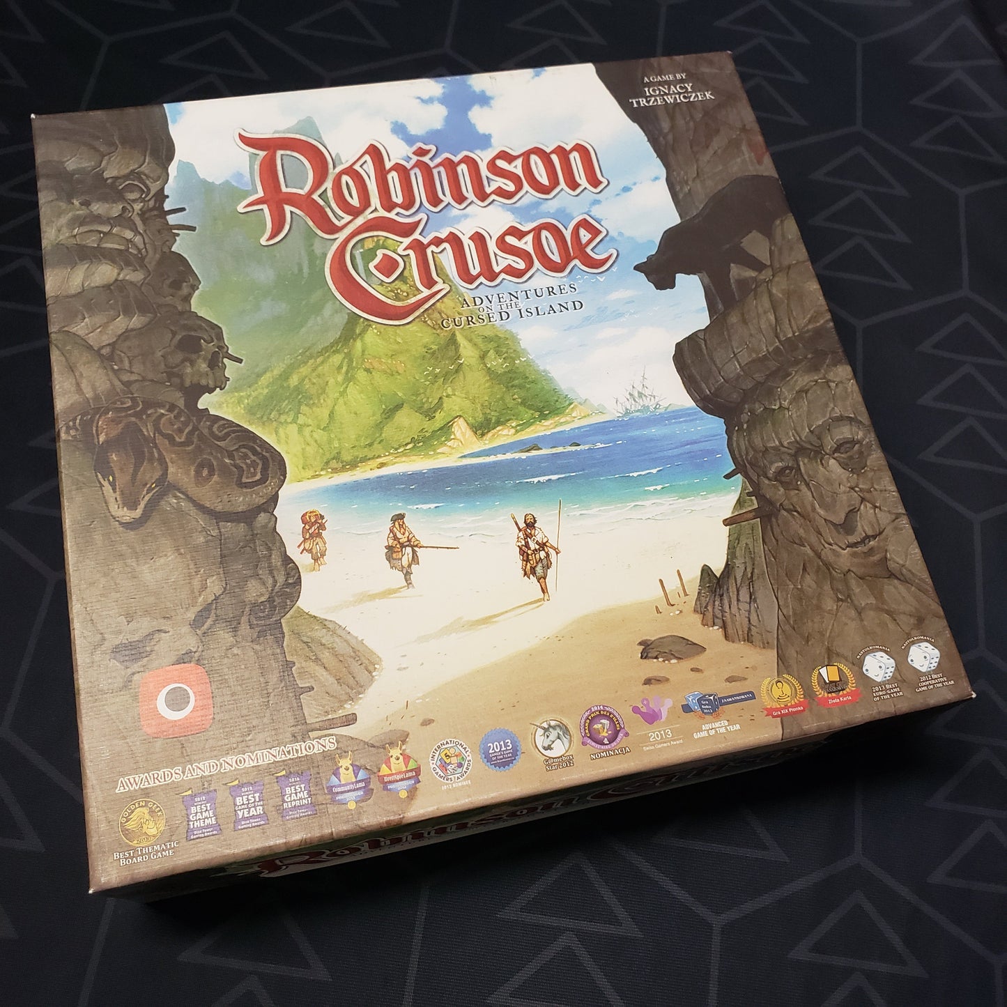 Image shows the front cover of the box of the Robinson Crusoe: Adventures on the Cursed Island board game