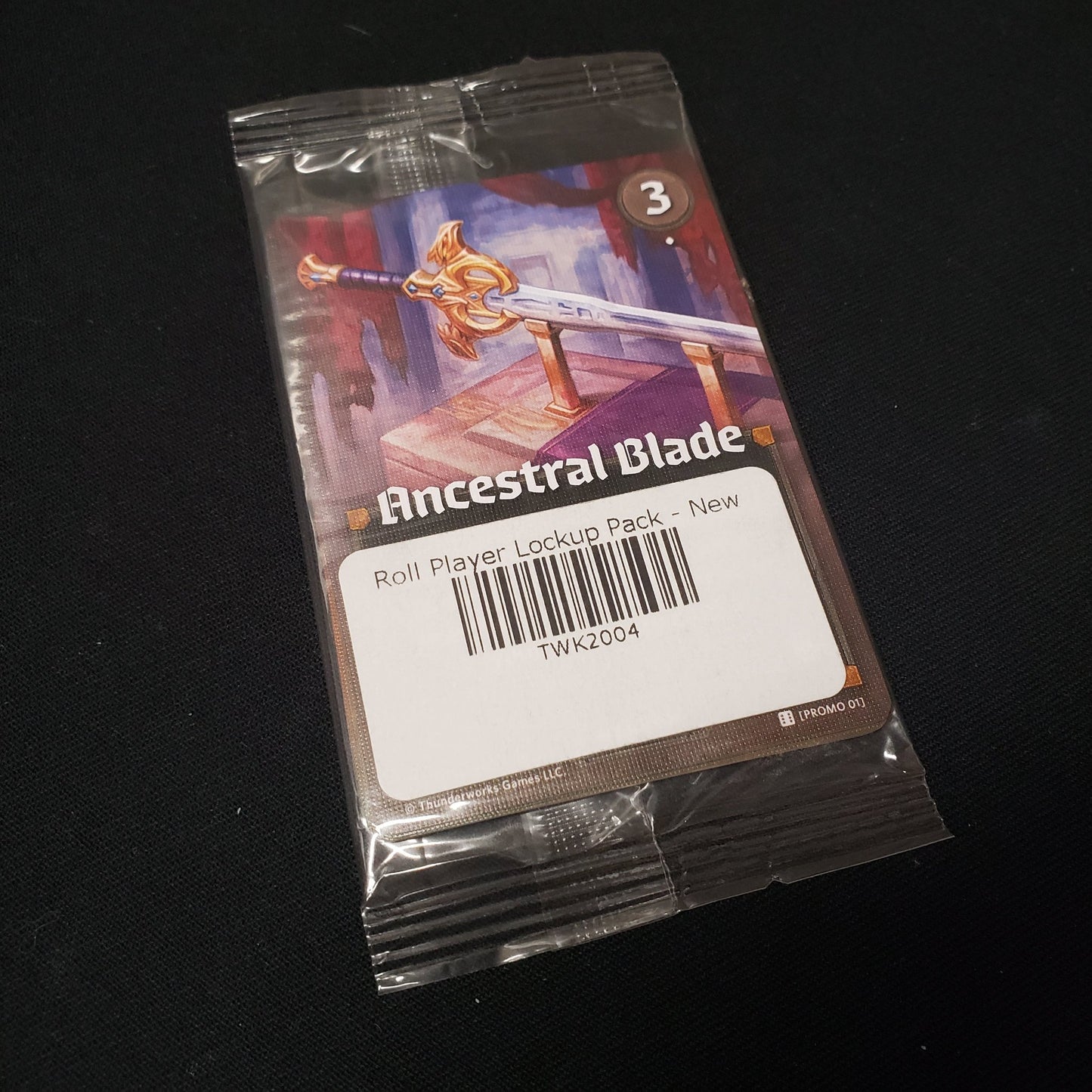 Image shows a card inside the clear plastic packaging of the Lockup Pack for the board game Roll PLayer