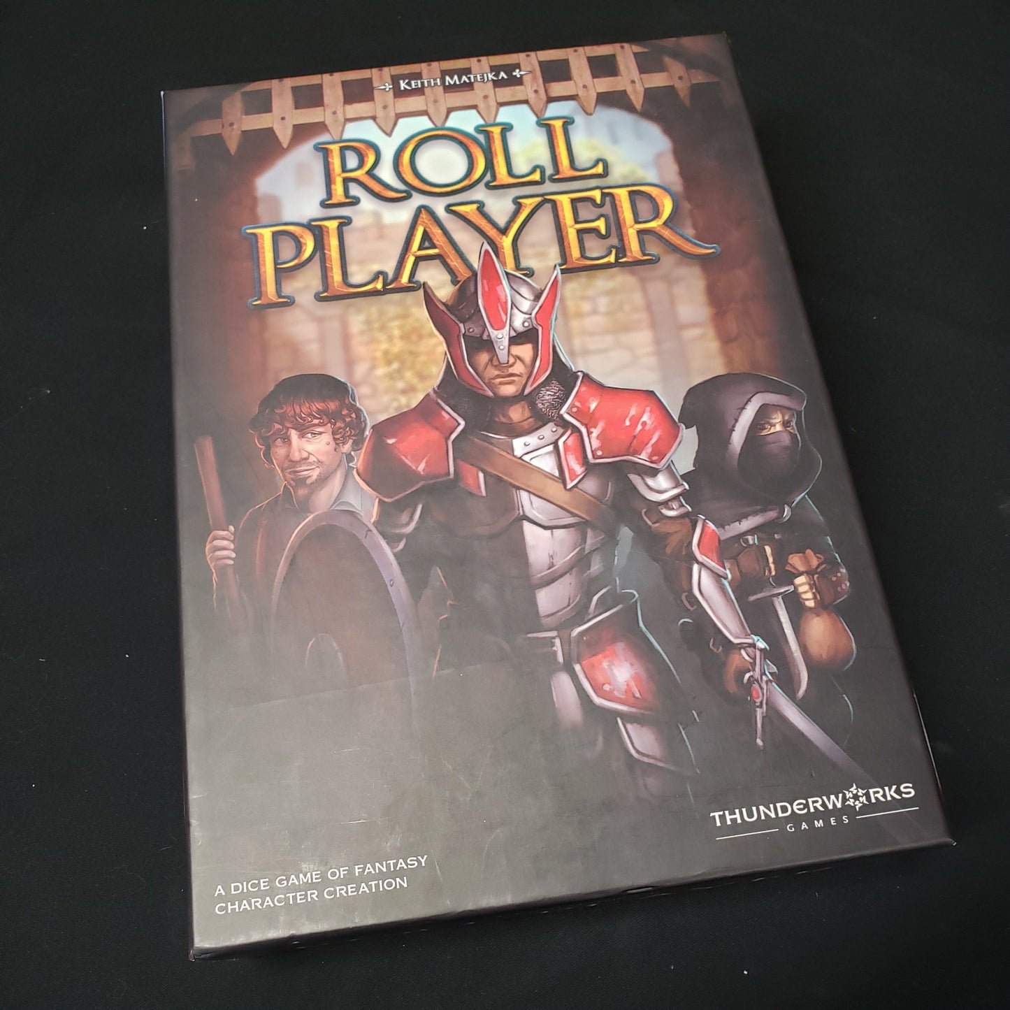 Image shows the front cover of the box of the Roll Player board game