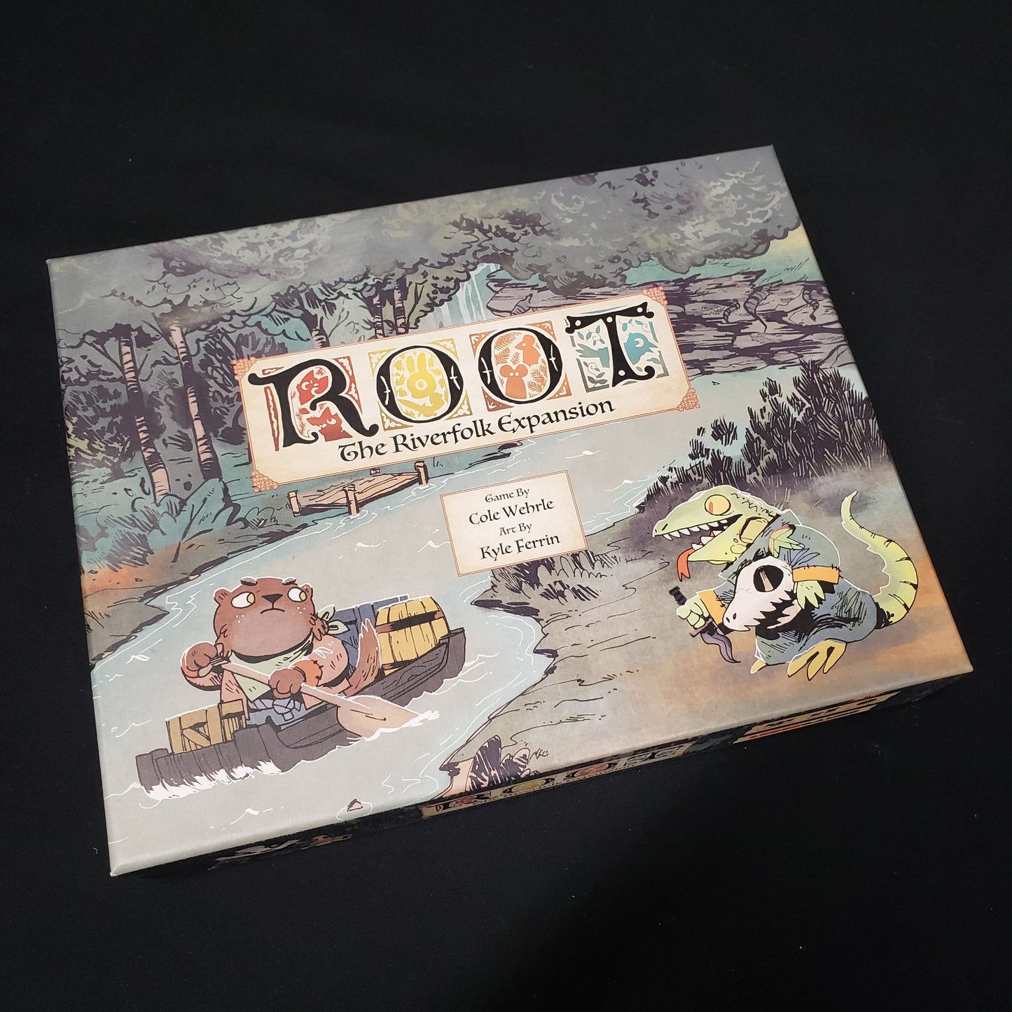 Image shows the front cover of the box for the Riverfolk expansion from the board game Root
