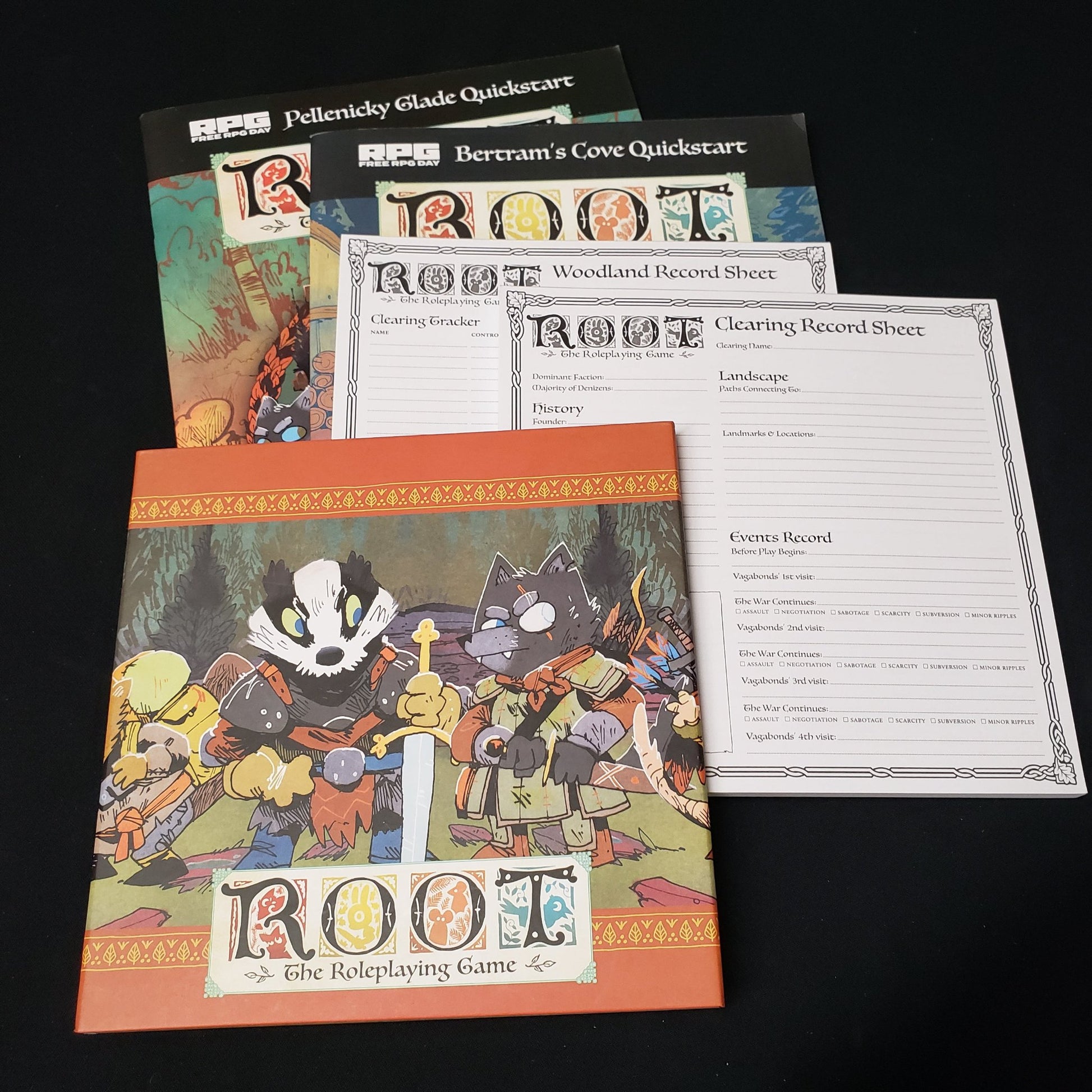 Image shows a GM screen, character pads, and quickstart guides for theroleplaying game Root