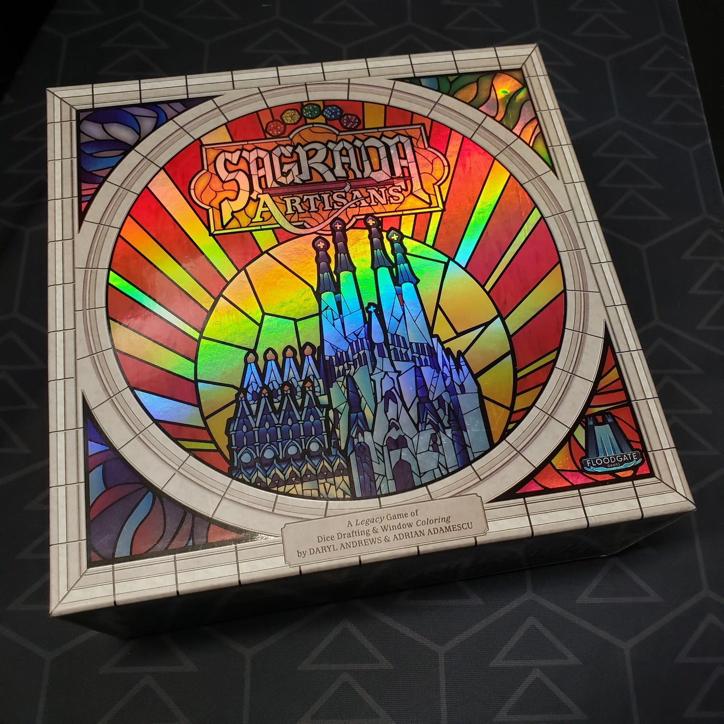 Image shows the front cover of the box of the Sagrada Artisans board game