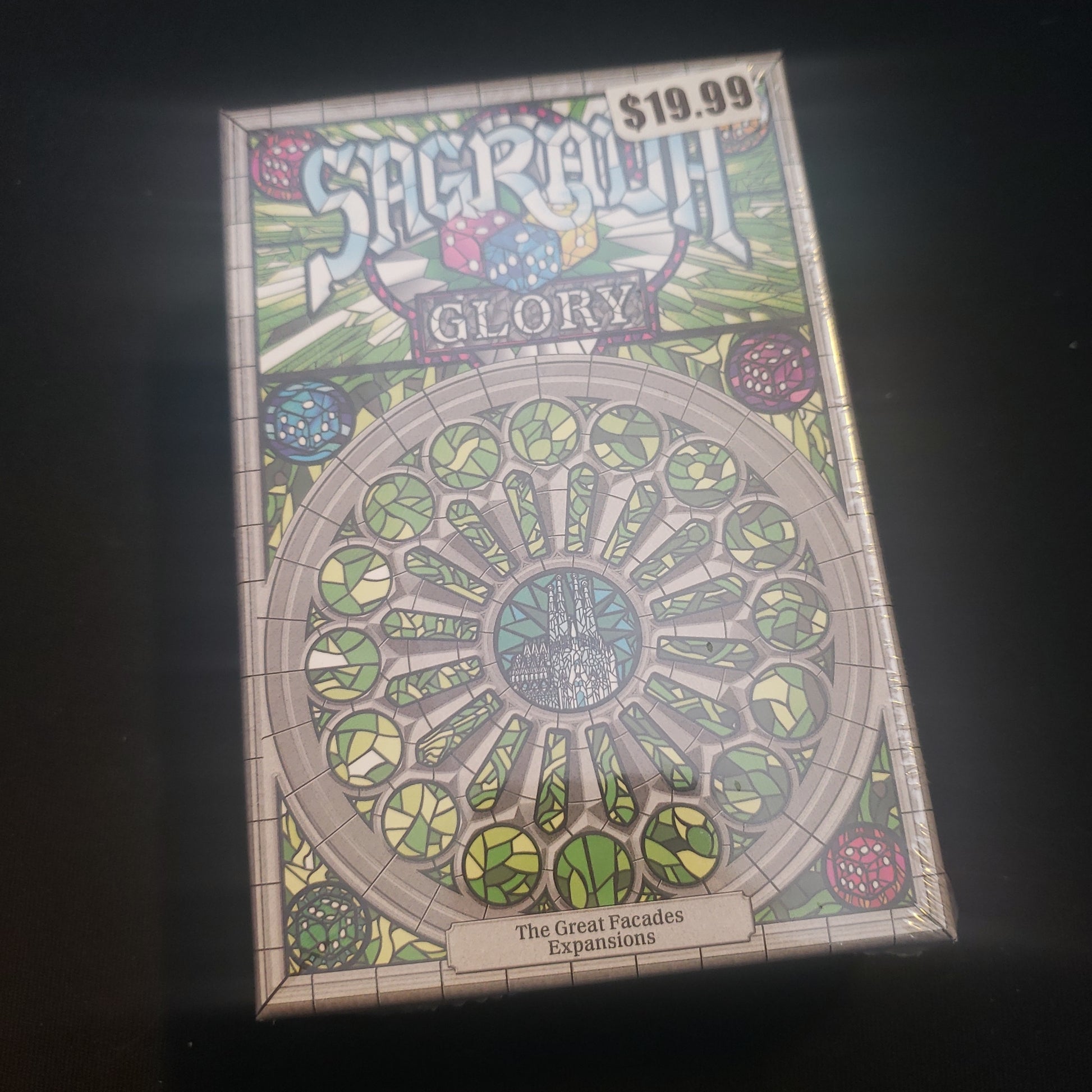 Image shows the front cover of the box of the Glory expansion for the board game Sagrada