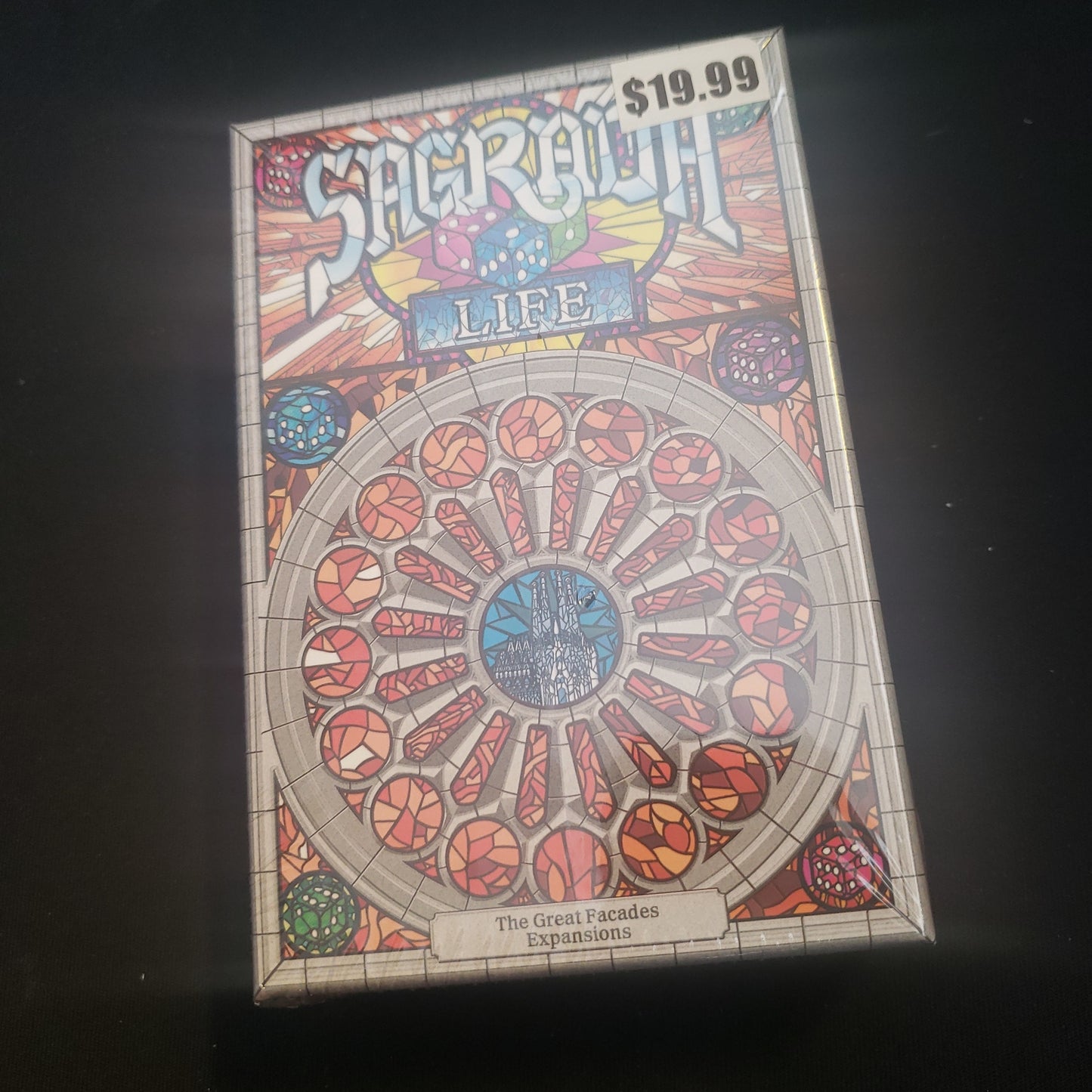 Image shows the front cover of the box of the Life expansion for the board game Sagrada