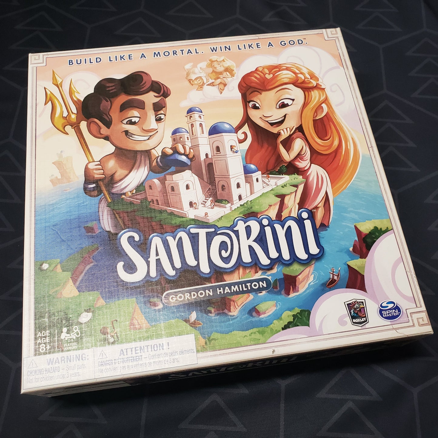 Image shows the front cover of the box of the Santorini board game