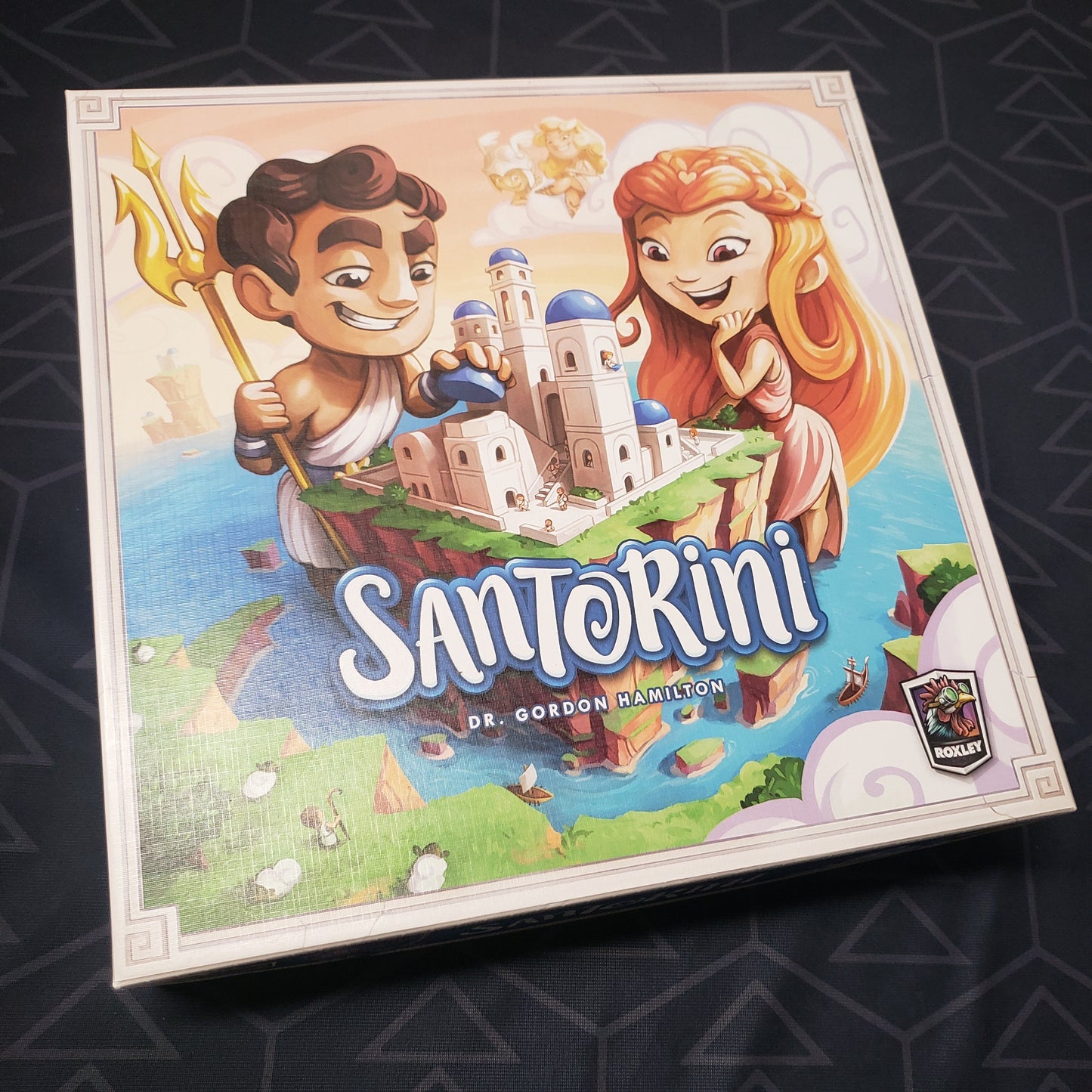Image shows the front cover of the box of the Santorini board game
