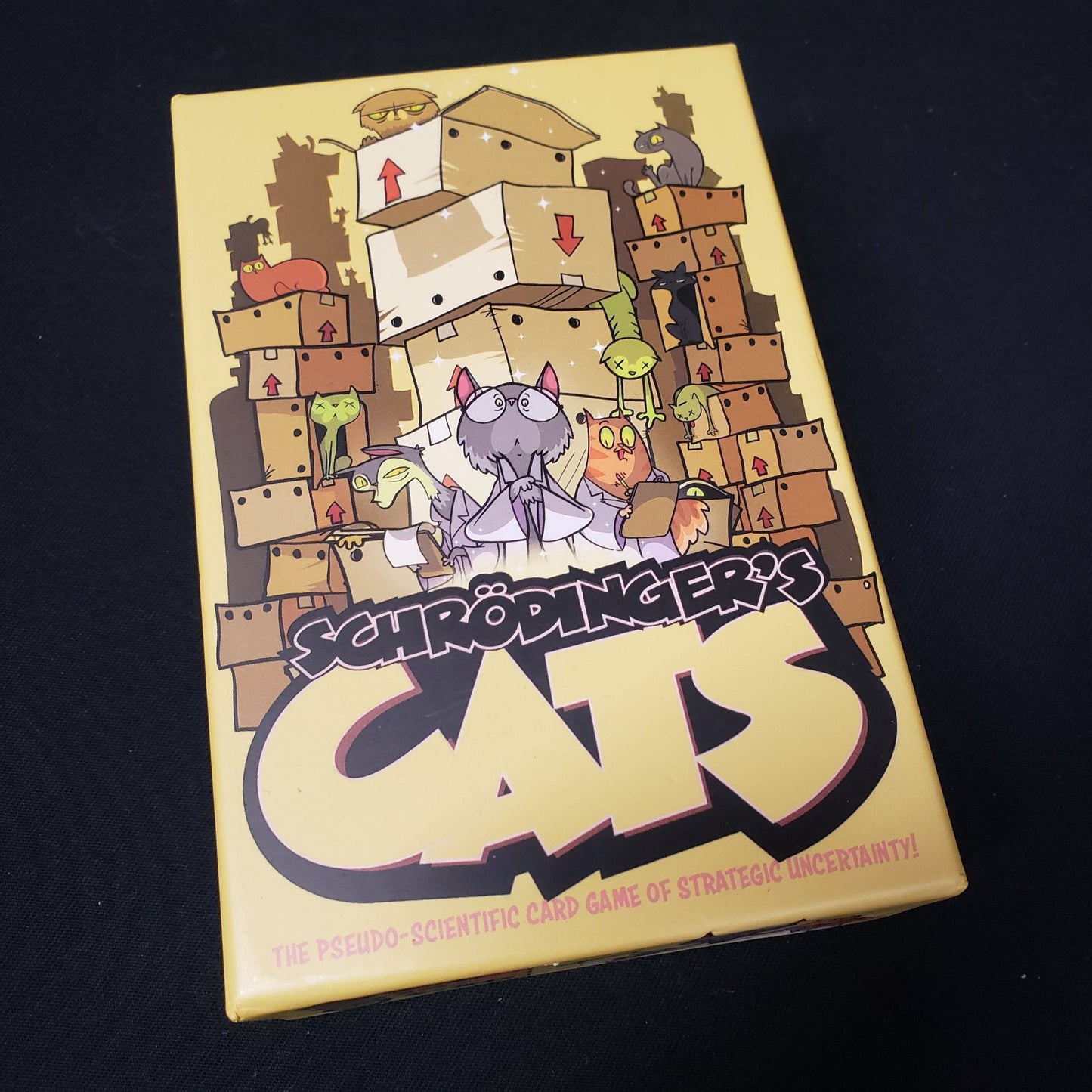 Image shows the front cover of the box of the Schrodinger's Cats card game