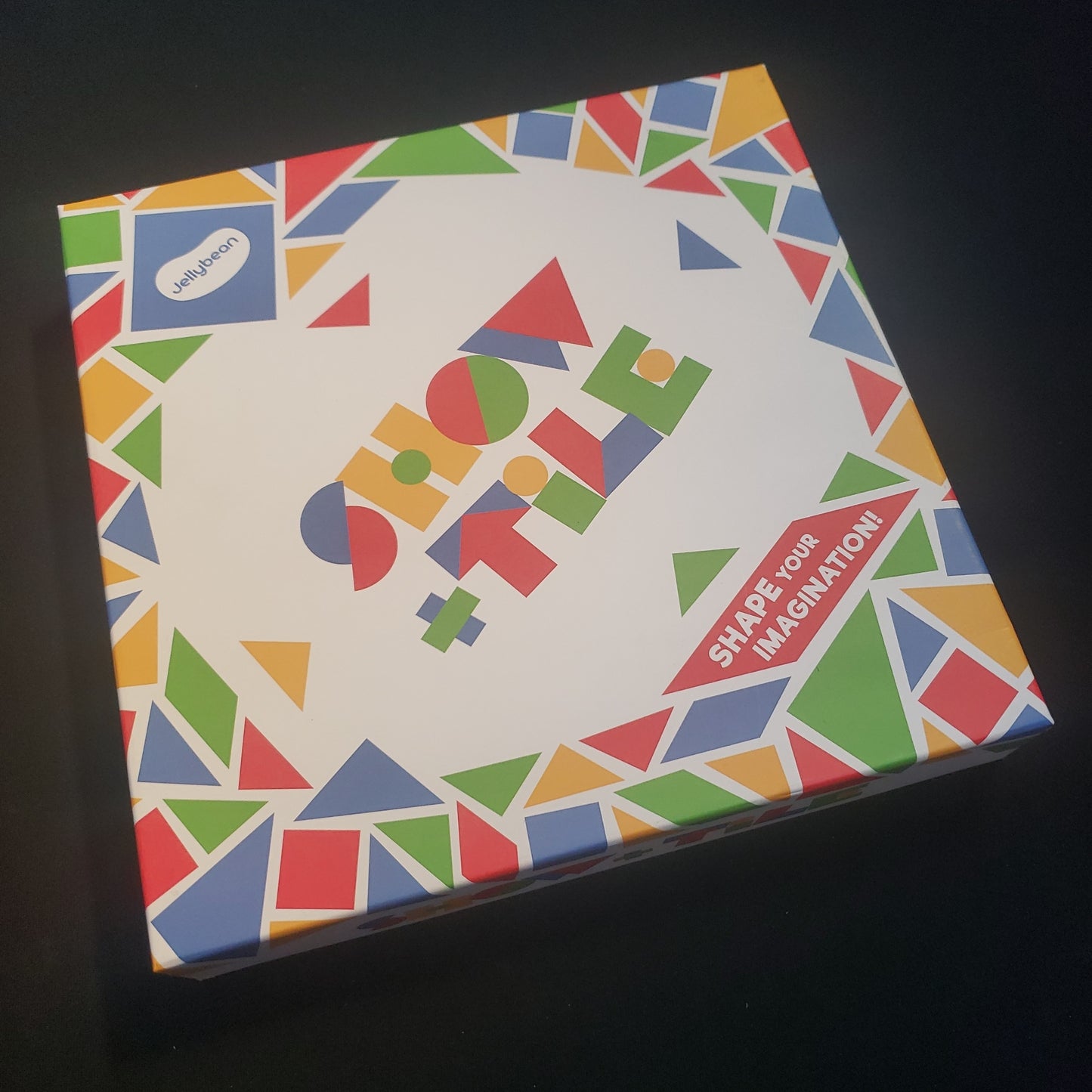 Image shows the front cover of the box of the Show and Tile board game