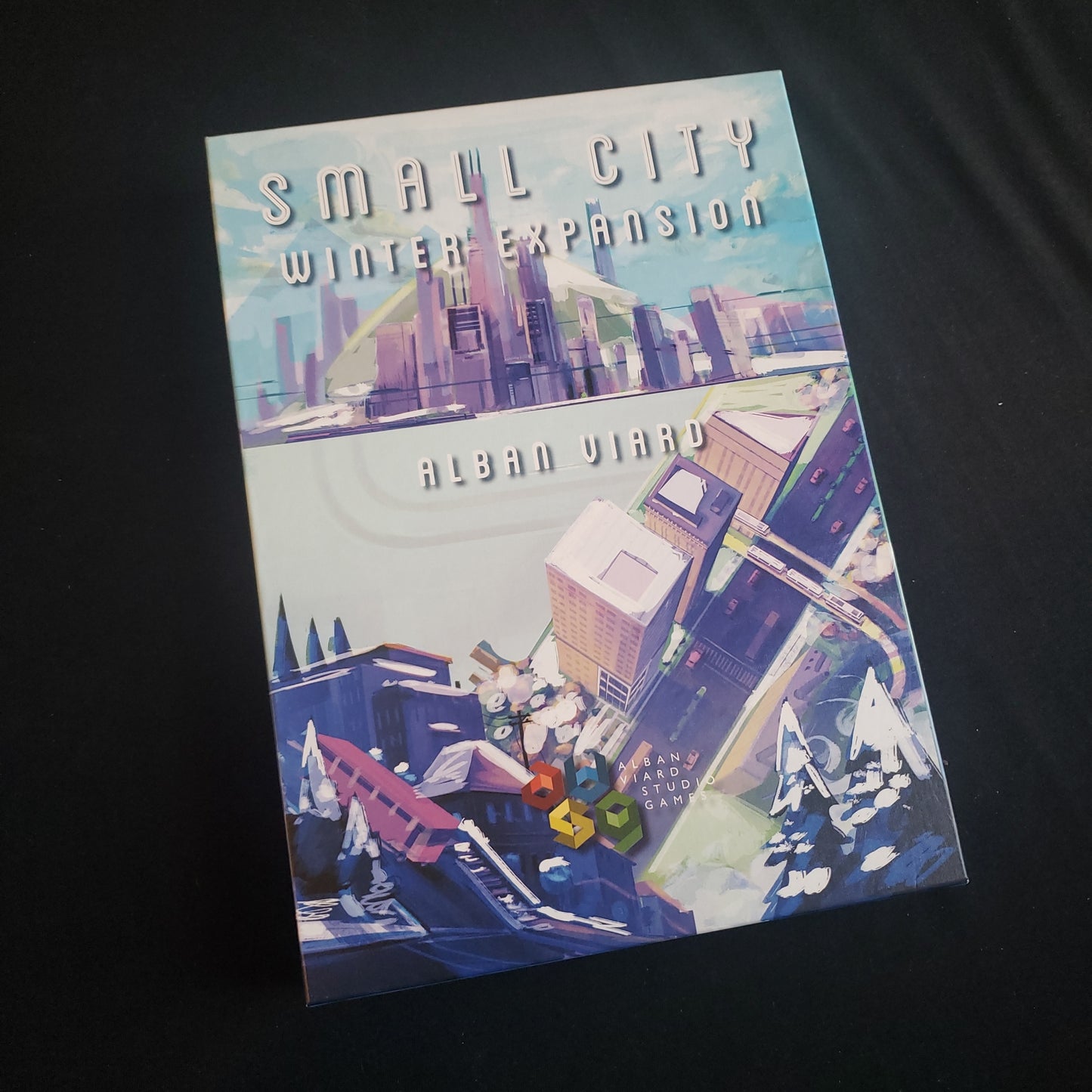 Image shows the front cover of the box of the Winter Expansion for the board game Small City: Deluxe Edition