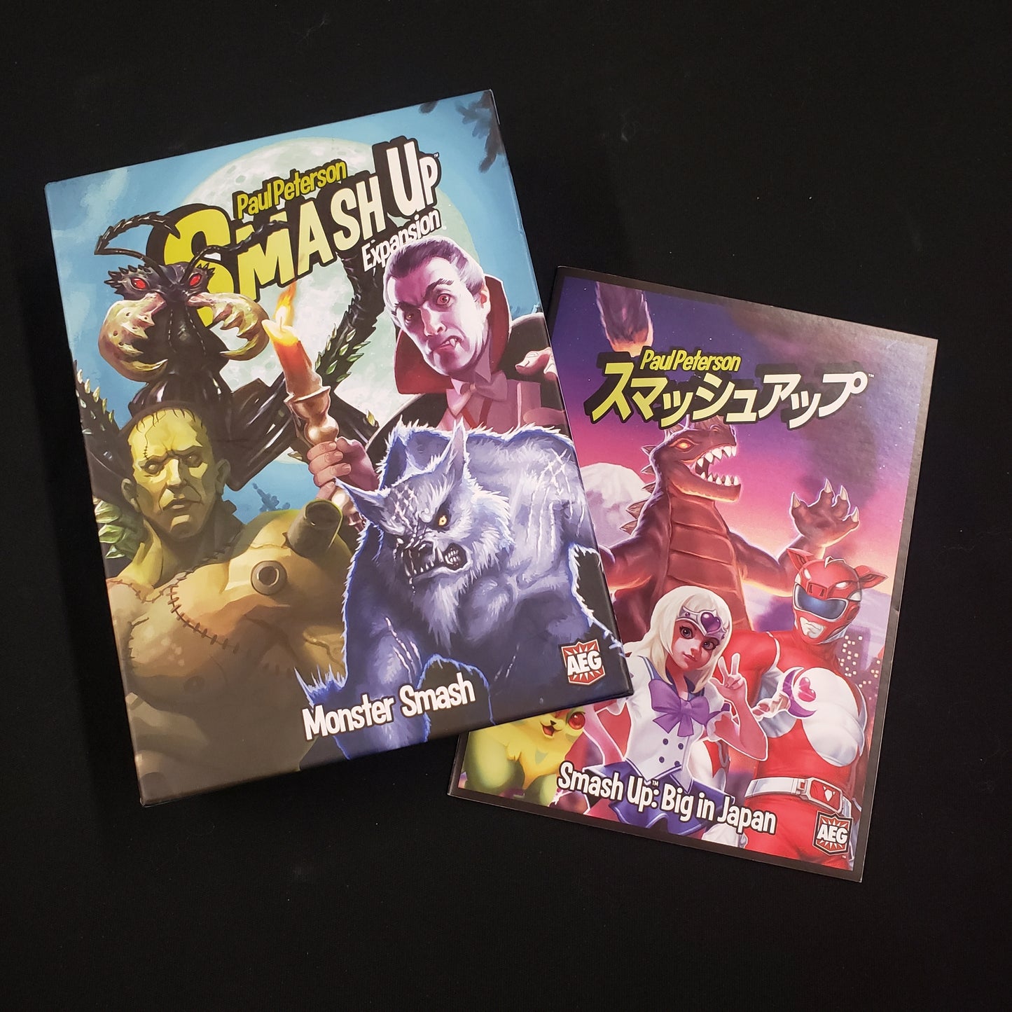 Image shows the front cover of the box of the Monster Smash expansion for the card game Smash Up, sitting on top of the instructions for the Big in Japan expansion