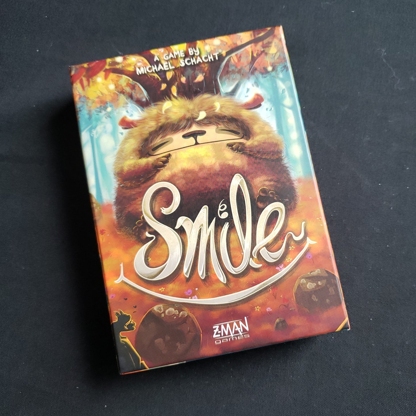 Image shows the front cover of the box of the Smile card game