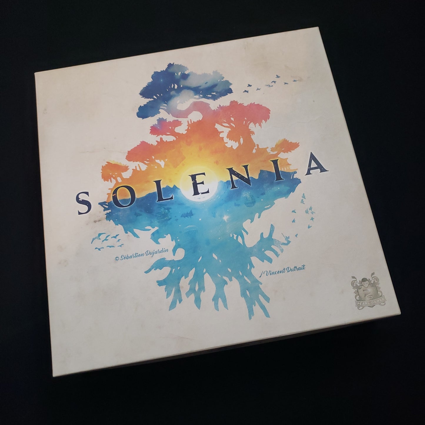 Image shows the front cover of the box of the Solenia board game