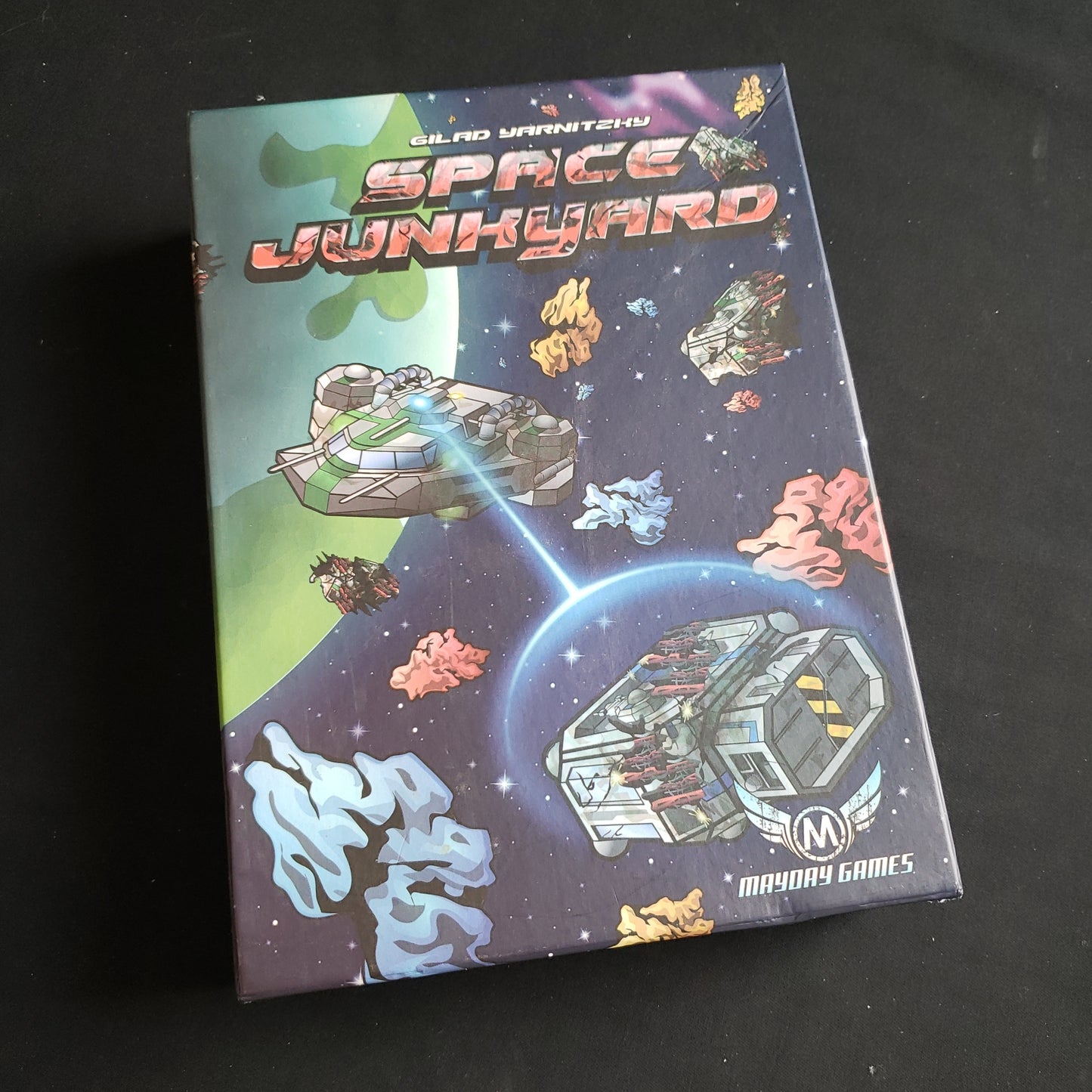 Image shows the front cover of the box of the Space Junkyard board game