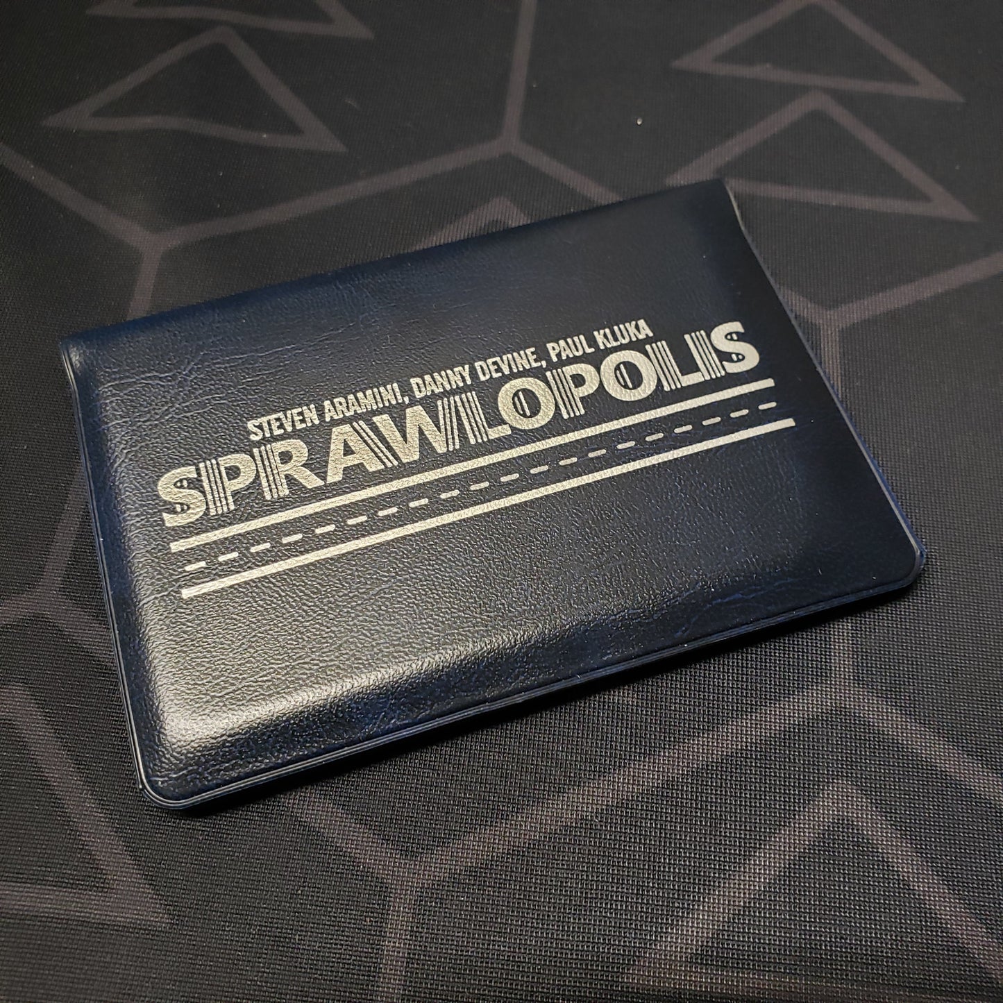 Image shows the front cover of the card wallet of the Sprawlopolis card game