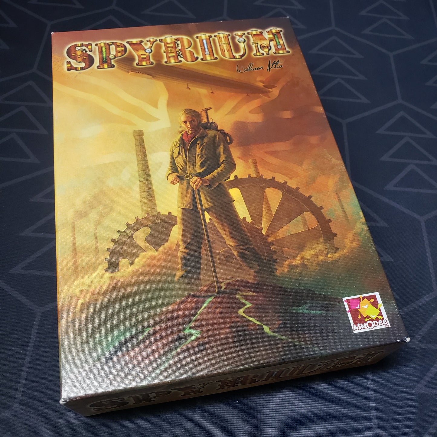 Image shows the front cover of the box of the Spyrium board game