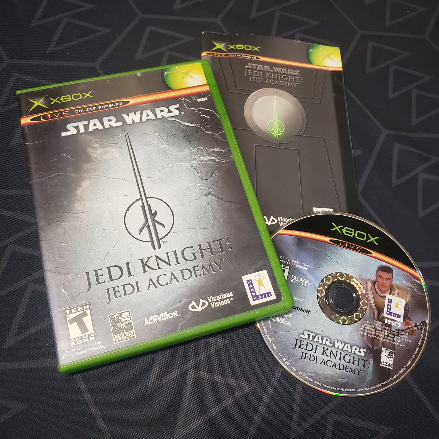 Image shows the case, manual and disc for the video game Star Wars Jedi Knight: Jedi Academy for the original Xbox