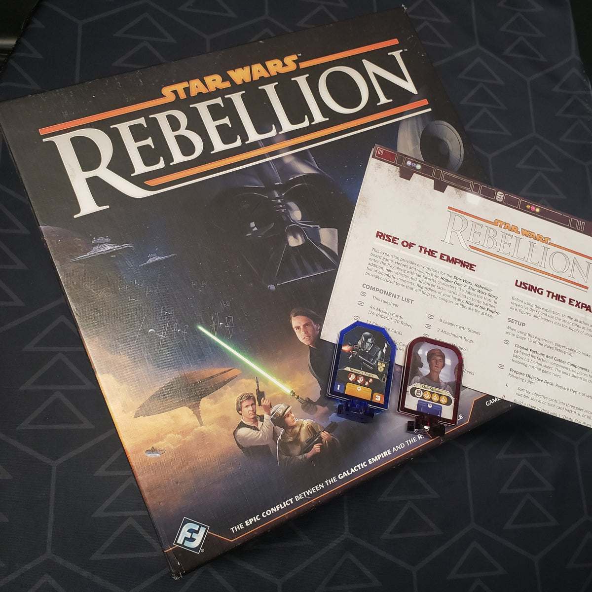 Image shows the front cover of the box of the Star Wars: Rebellion board game along with an expansion manual and some upgraded components