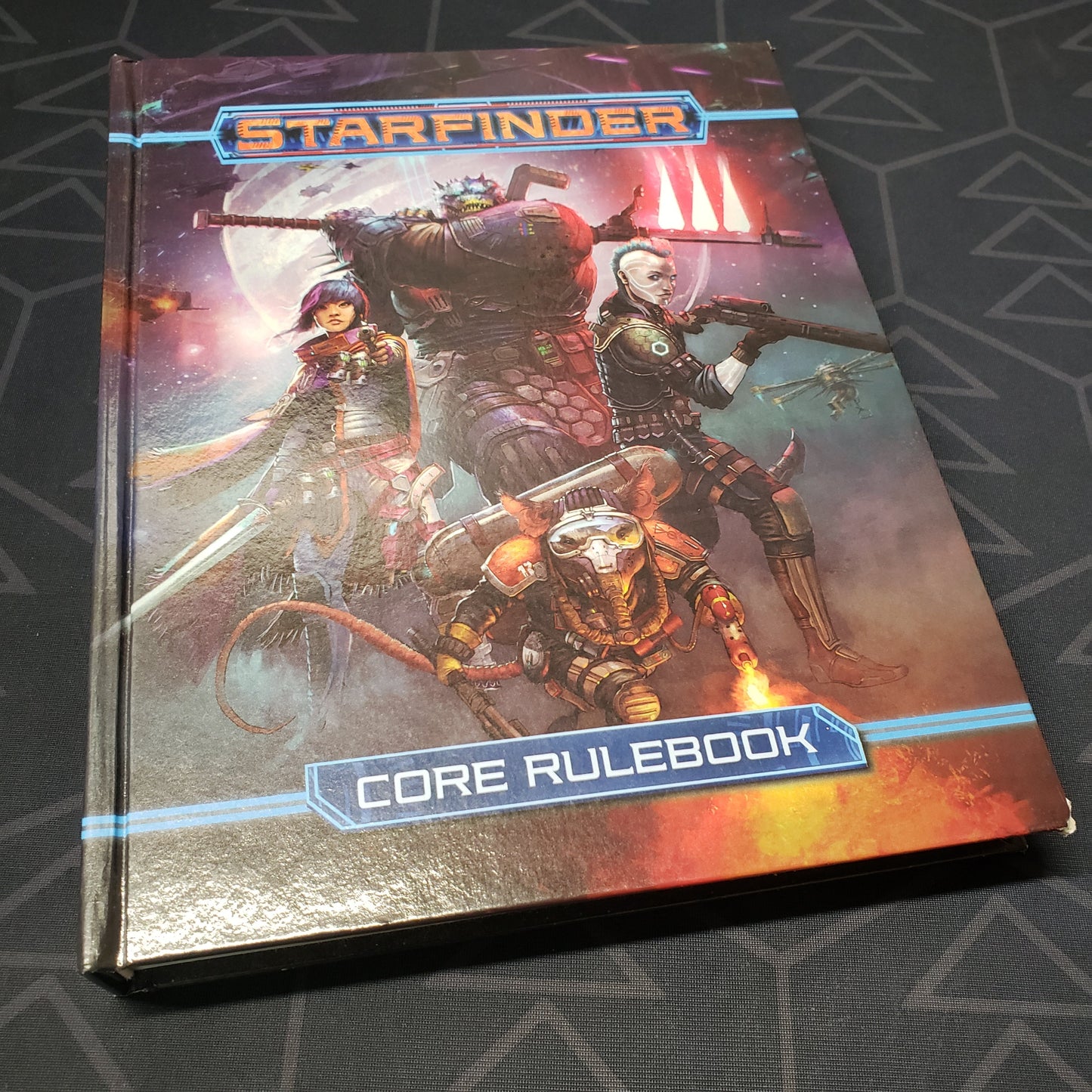 Image shows the front cover of the core rulebook for the roleplaying game Starfinder: First Edition