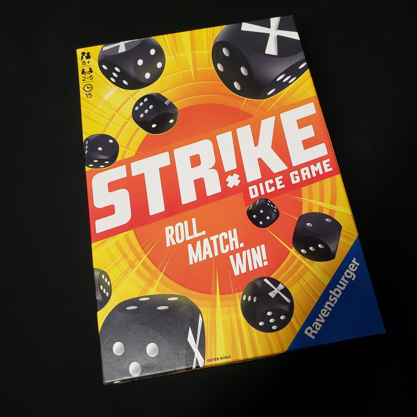 Image shows the front cover of the box of the Strike dice game