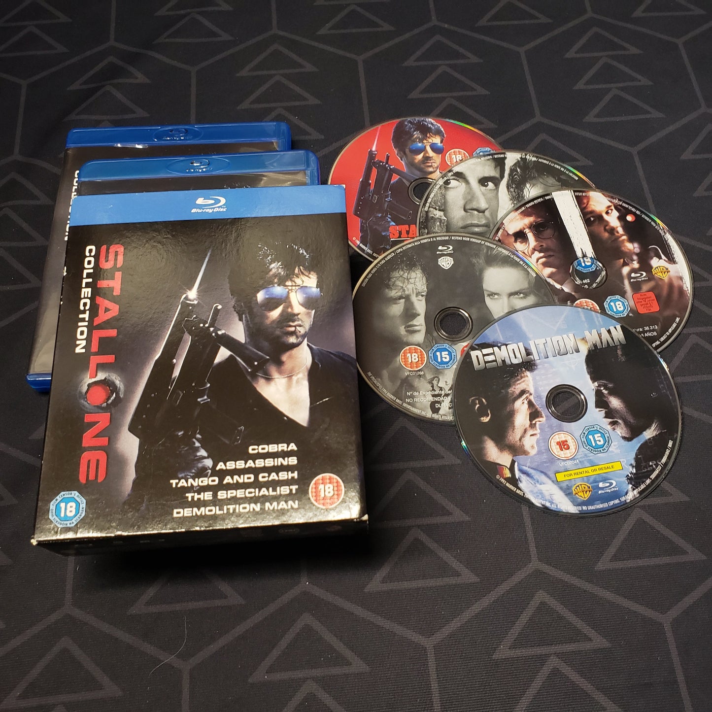 Image shows the cases, outer box & five discs for the Sylvester Stallone Collection movie set on Blu-Ray