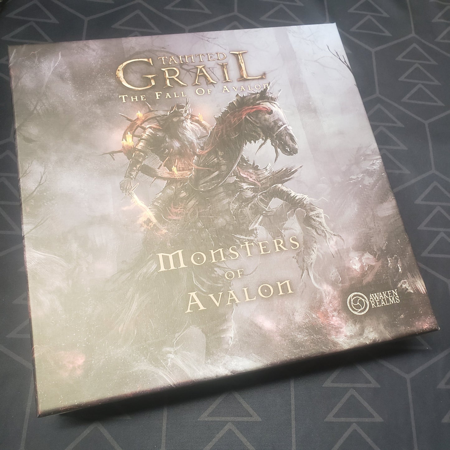Image shows the front cover of the box of the Monsters of Avalon expansion for the board game Tainted Grail
