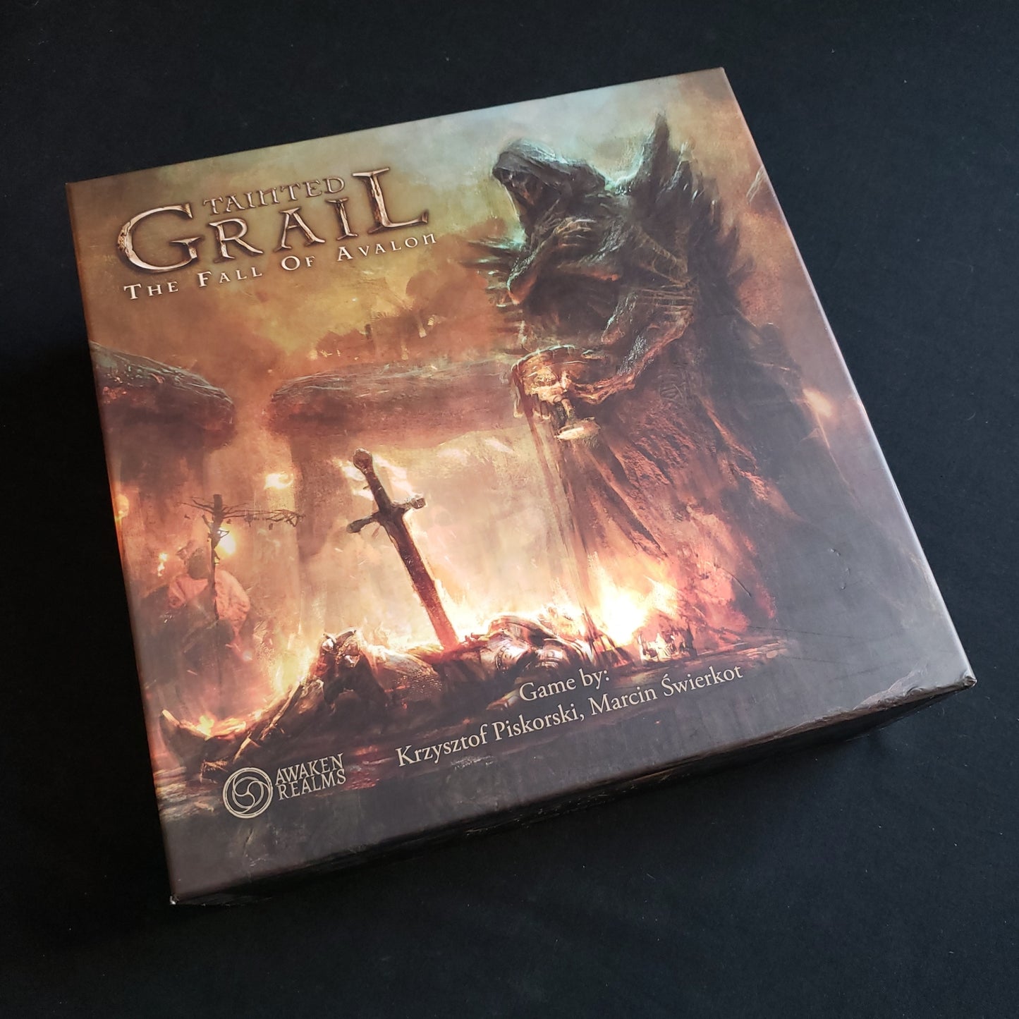 Image shows the front cover of the box of the Tainted Grail board game