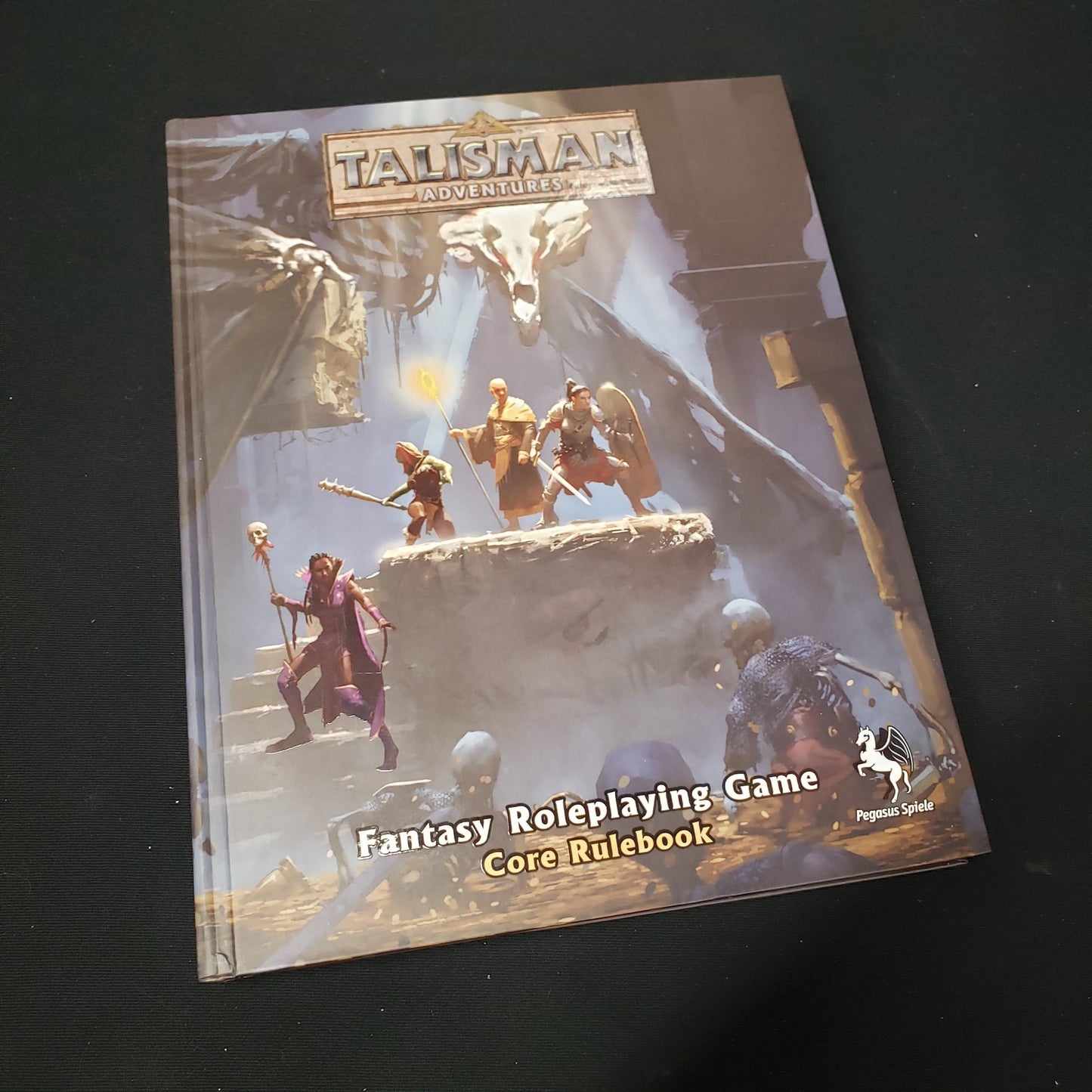 Image shows the front cover of the core rulebook for the roleplaying game Talisman Adventures