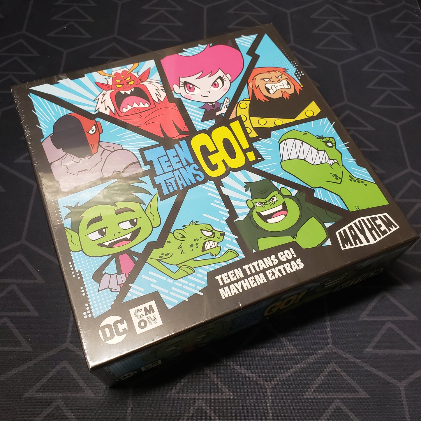 Image shows the front cover of the box of the Extras Box expansion for the board game Teen Titans GO! Mayhem