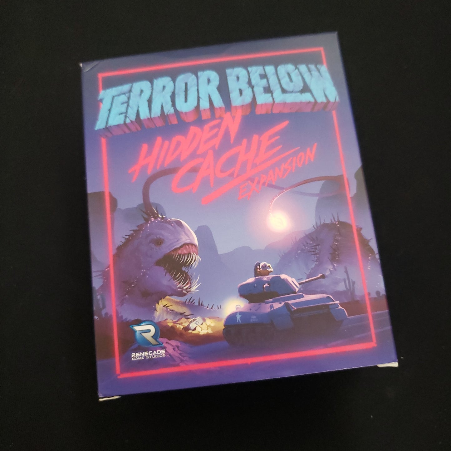 Image shows the front cover of the box of the Hidden Cache expansion for the board game Terror Below