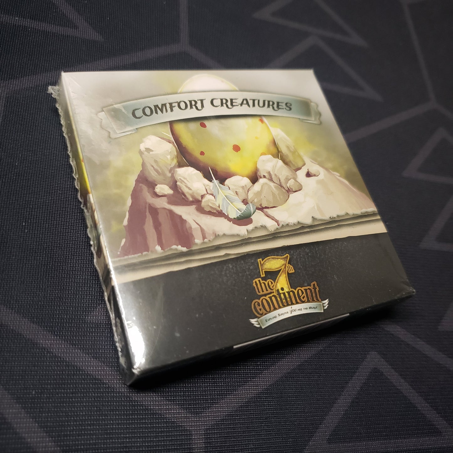 Image shows the front cover of the box of the Comfort Creatures expansion for the card game The 7th Continent