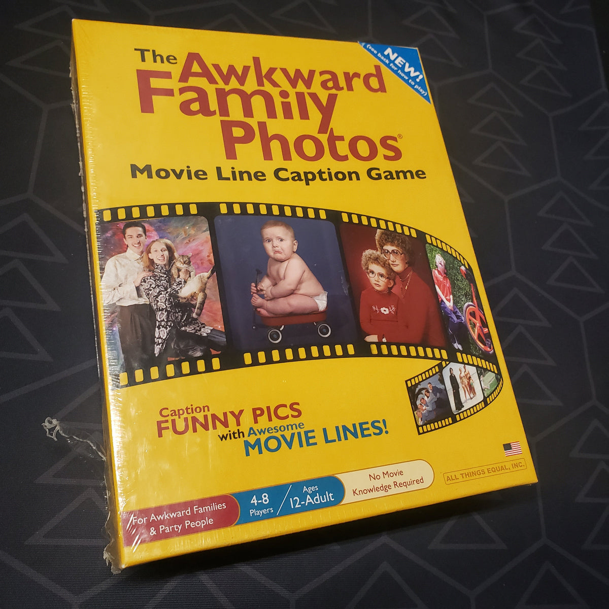 Image shows the front cover of the box for the party game Awkward Family Photos Movie Line Caption Game