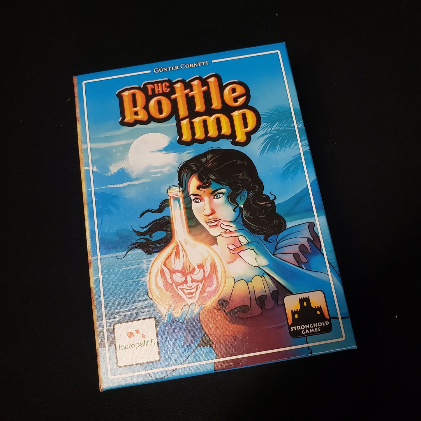 Image shows the front cover of the box of the Bottle Imp card game