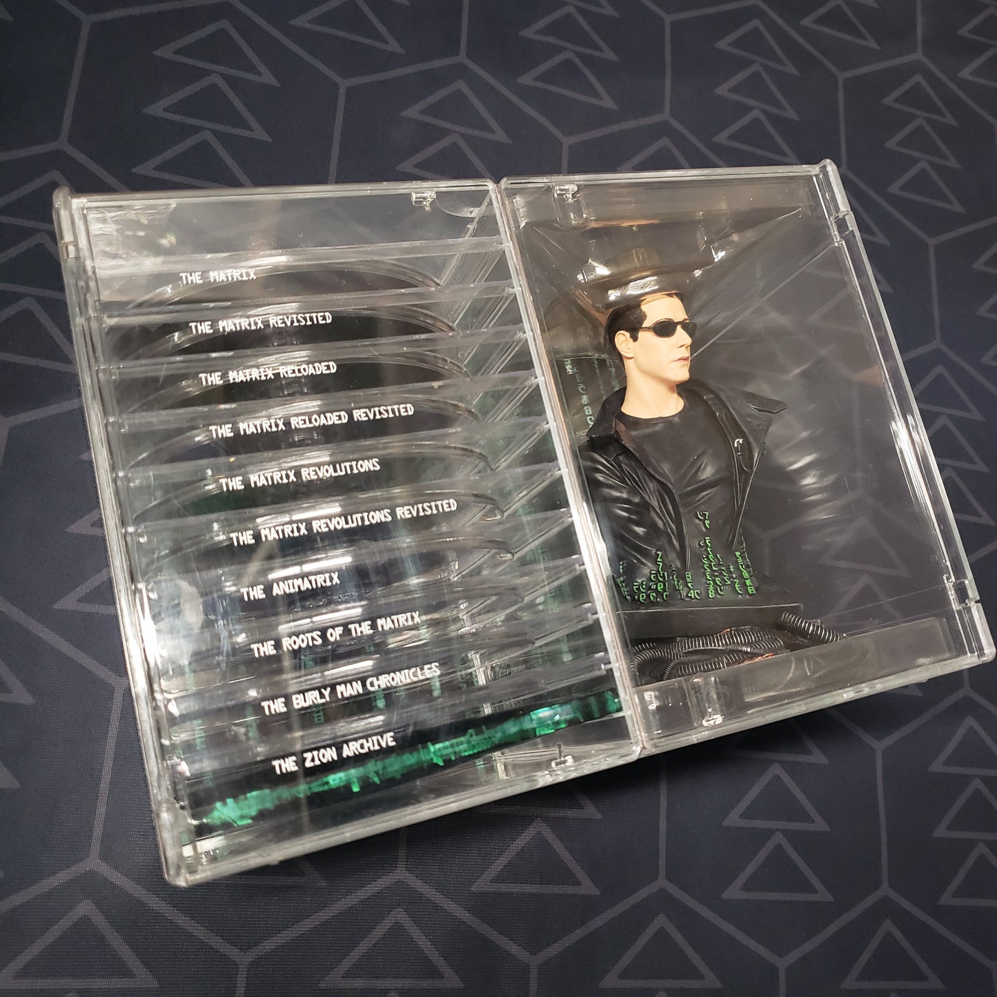 Image shows the front of the case for the Ultimate Matrix Collection set of movies on DVD with an included bust of Neo