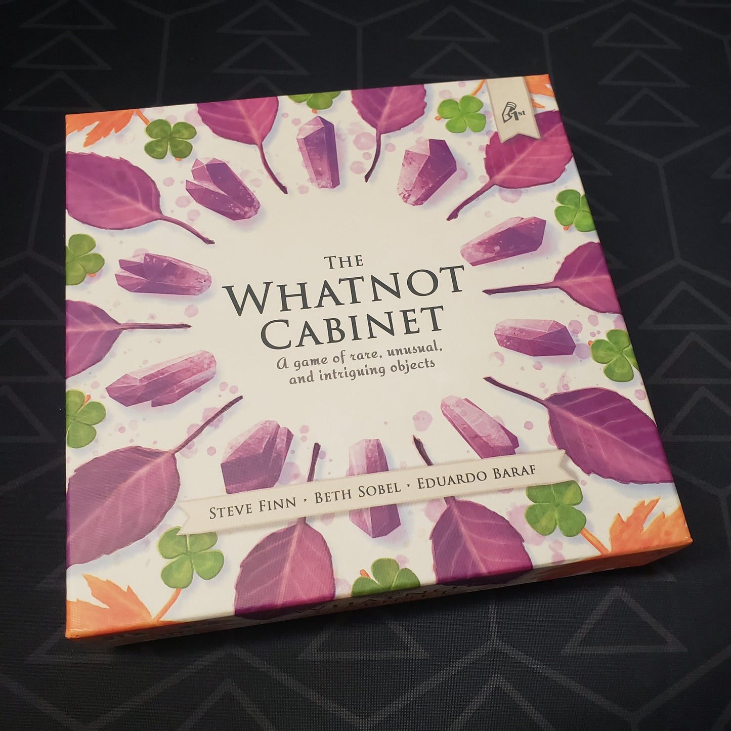 Image shows the front cover of the box for the board game The Whatnot Cabinet