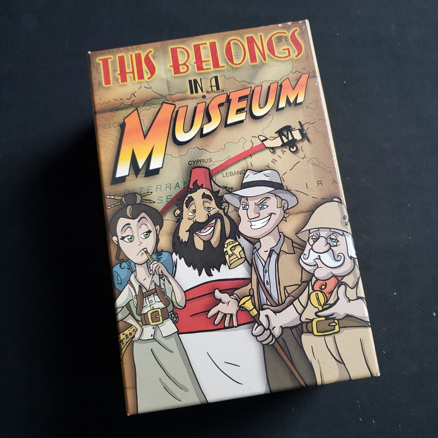 Image shows the front cover of the box of the This Belongs In A Museum board game