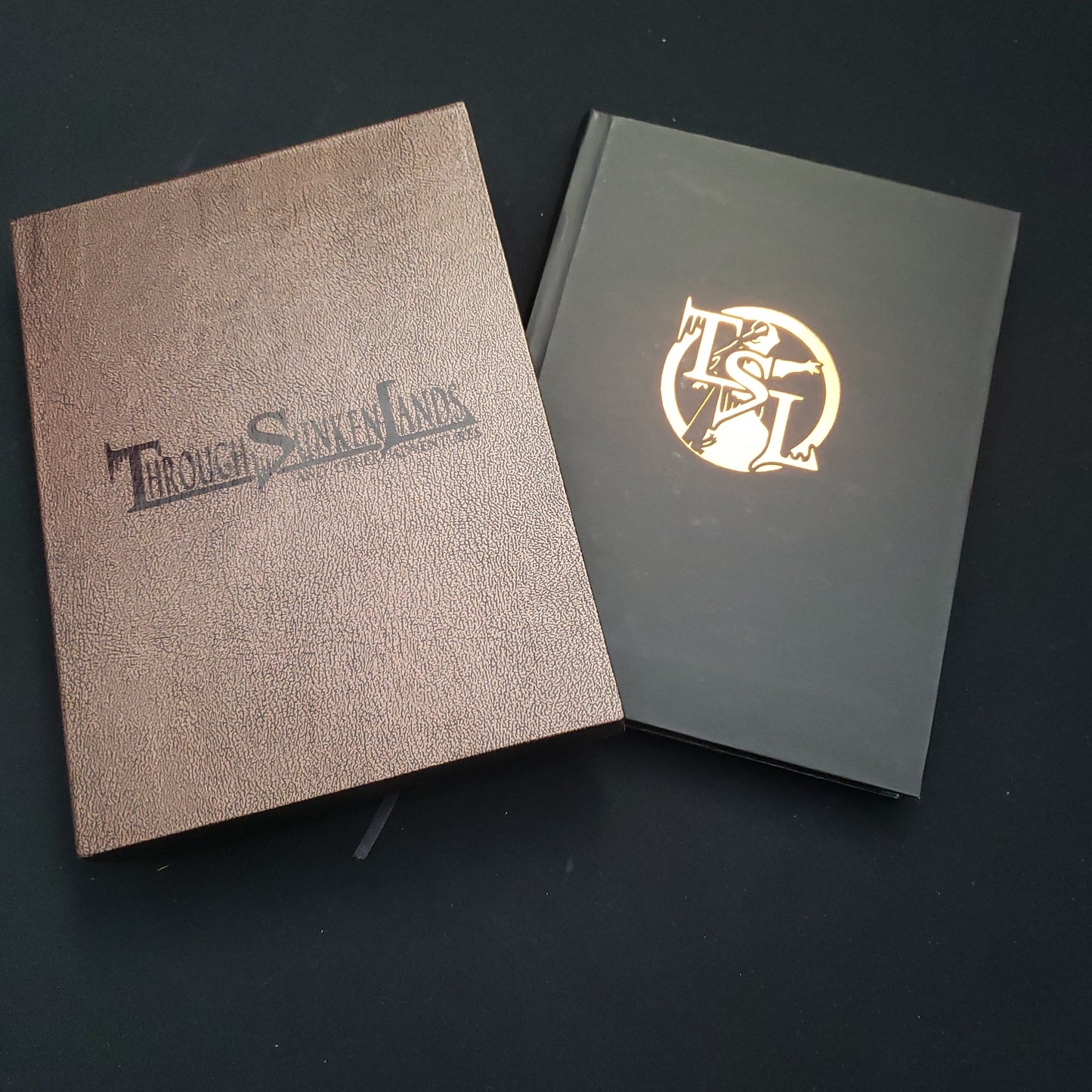 Image shows the front cover and slipcase for the Through Sunken Lands and Other Adventures roleplaying game book