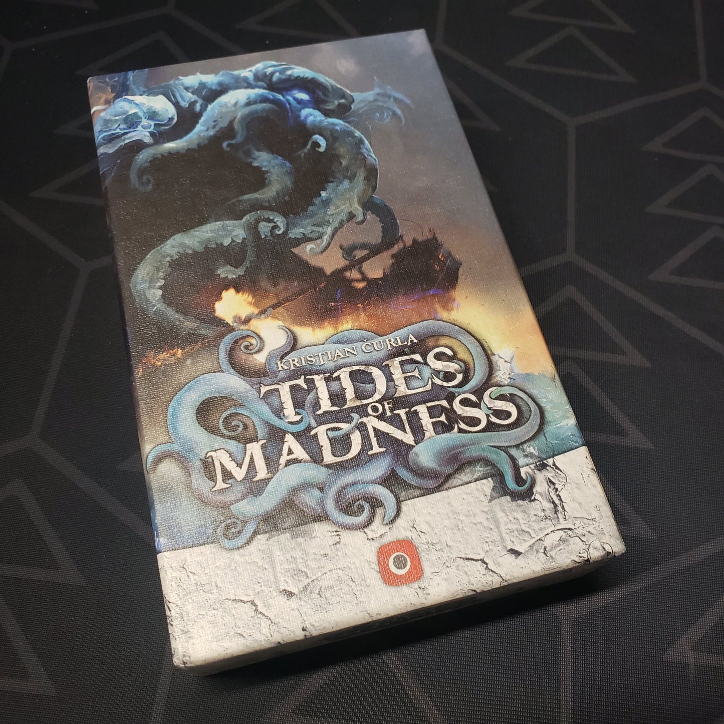 Image shows the front cover of the box of the Tides of Madness card game